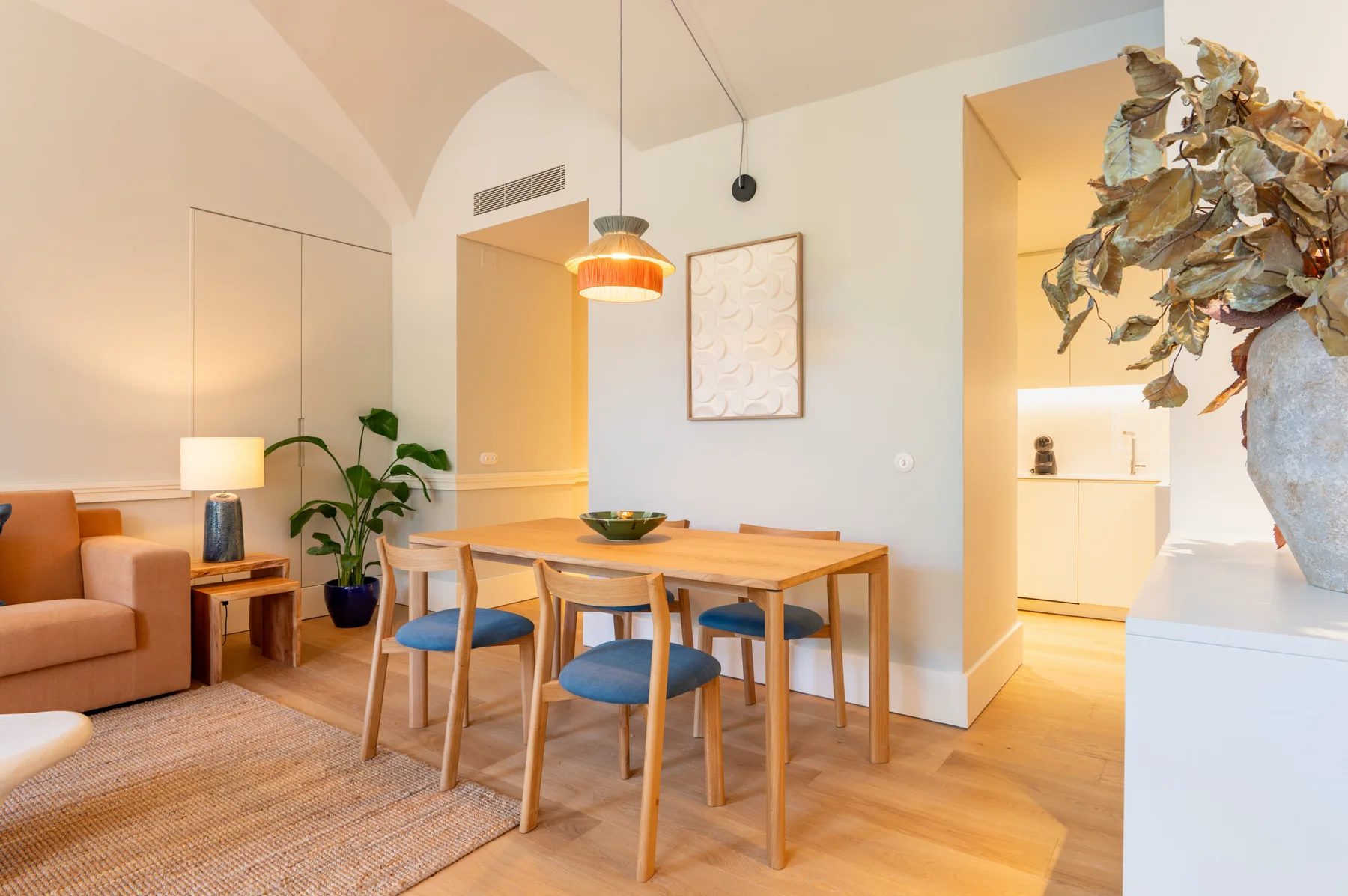 A dining area with a wooden table and blue seating beside a living area.