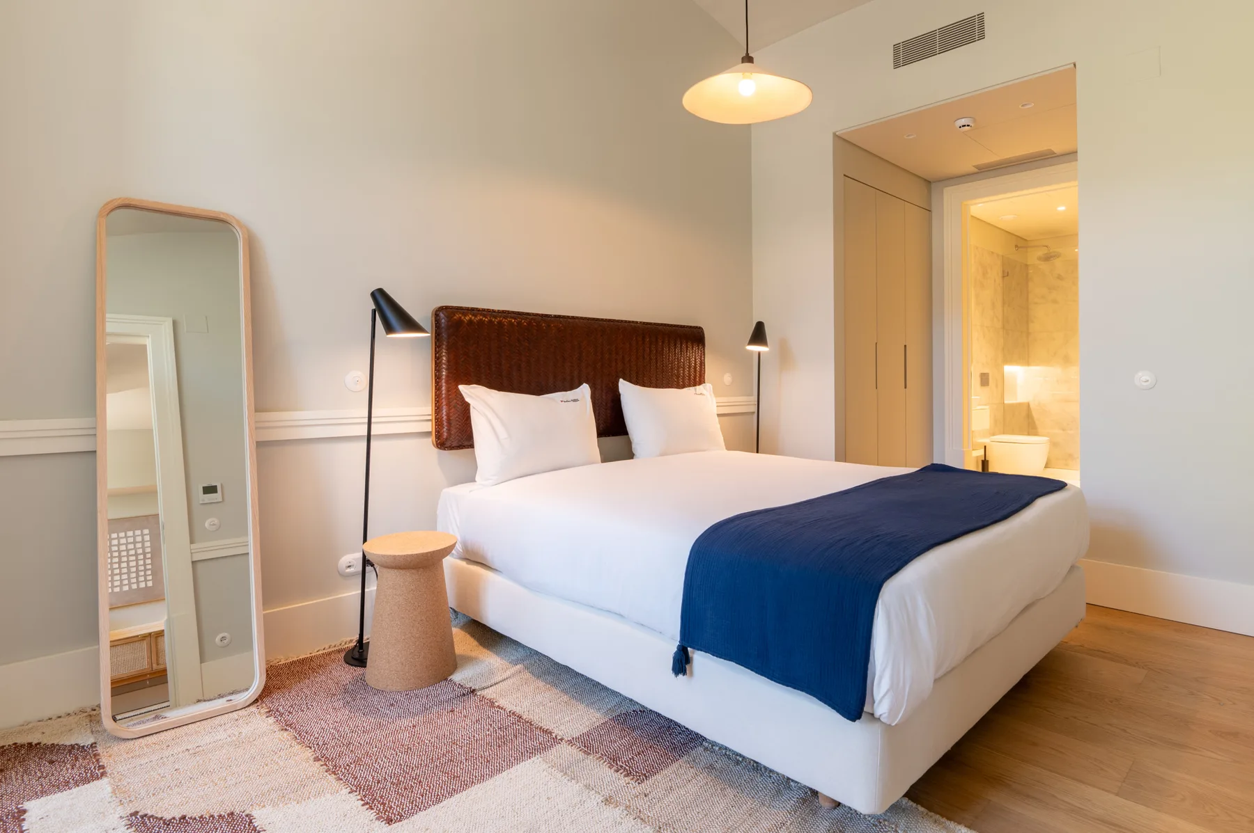 A bedroom with a double bed, white bedding, and a blue blanket.