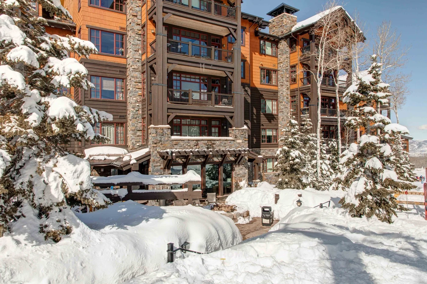 A multi-story building stands among snow-covered trees and deep snow.