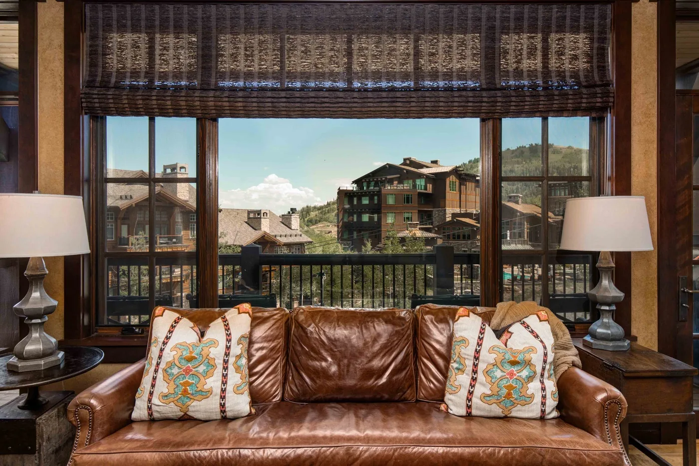 A living room seating area faces large windows with a view of nearby buildings.