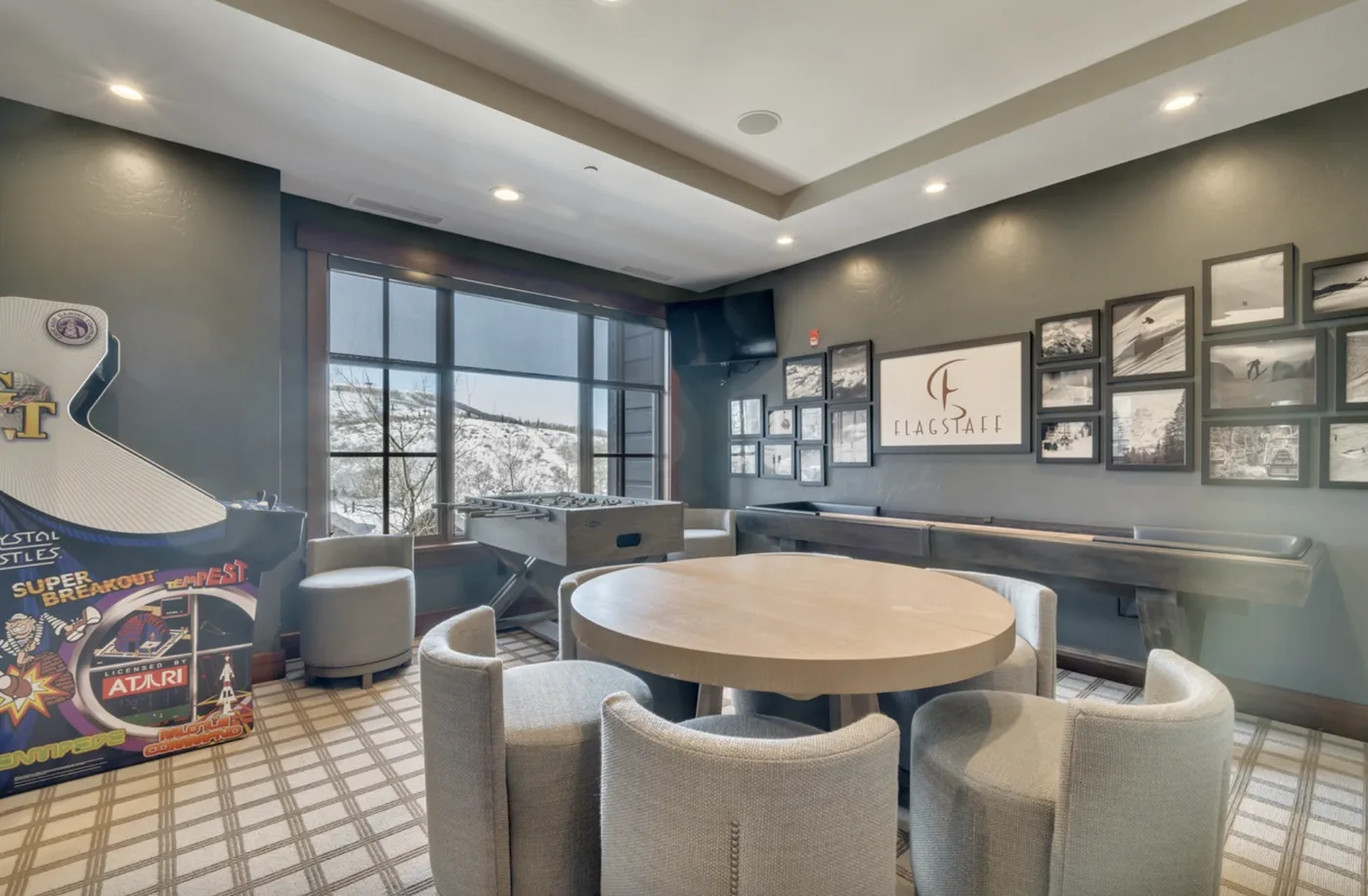 A lounge seating area with a round table, framed pictures, and large windows.
