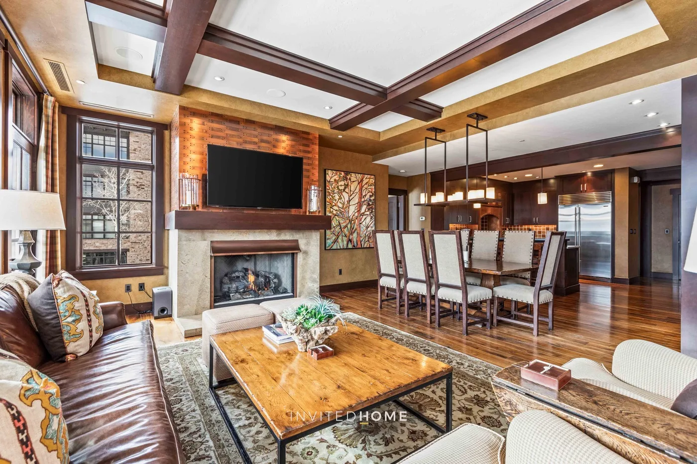An open-plan living and dining area features a fireplace and a large wooden table.