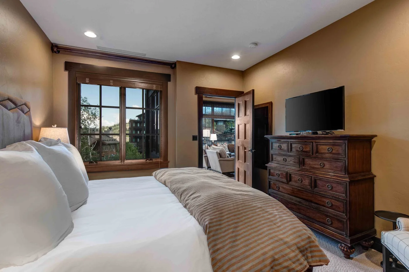 A bedroom with a bed, a dresser, and a television beside the window.