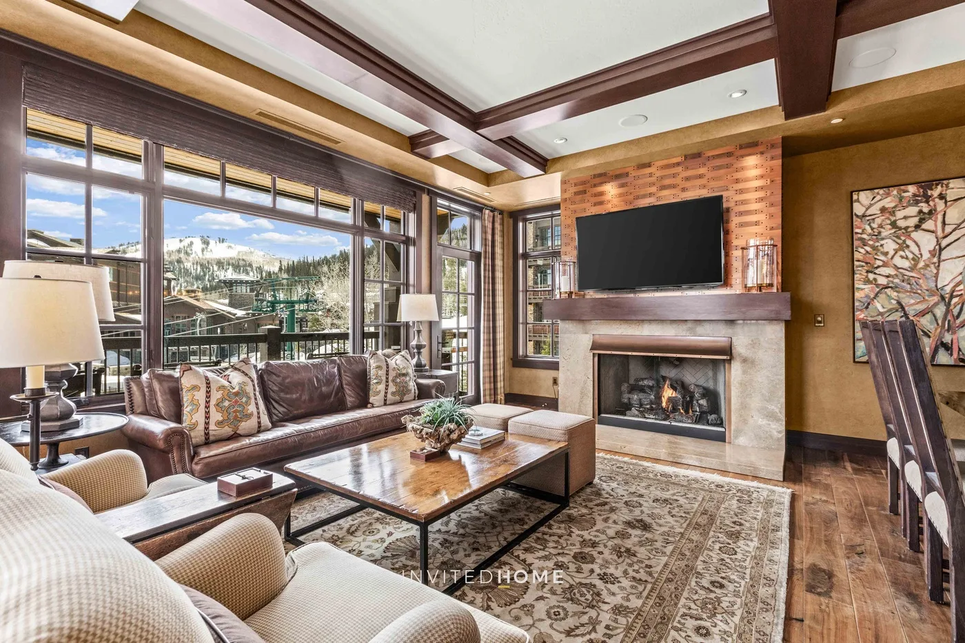 A living room with seating, a fireplace, and large windows overlooking the outdoors.