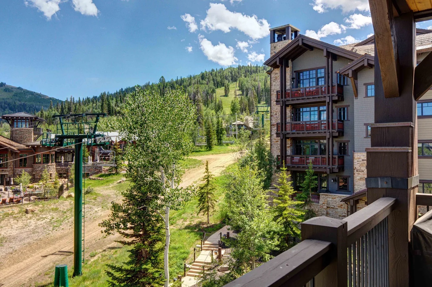 A mountain resort scene with multi-story buildings, trees, and a dirt path.