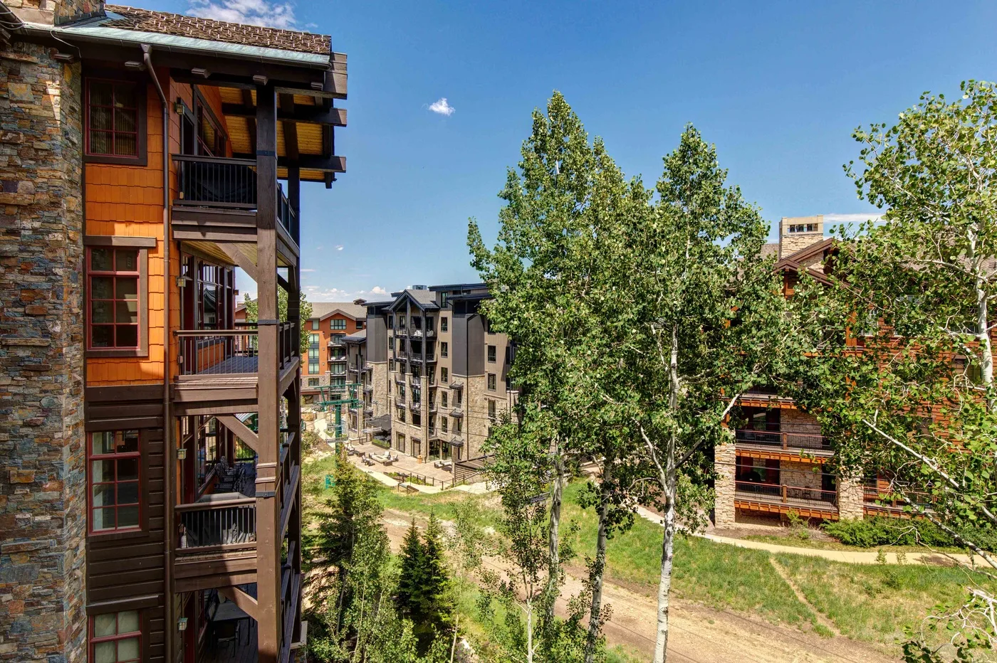 A cluster of multistory buildings stands among trees beneath a clear blue sky.
