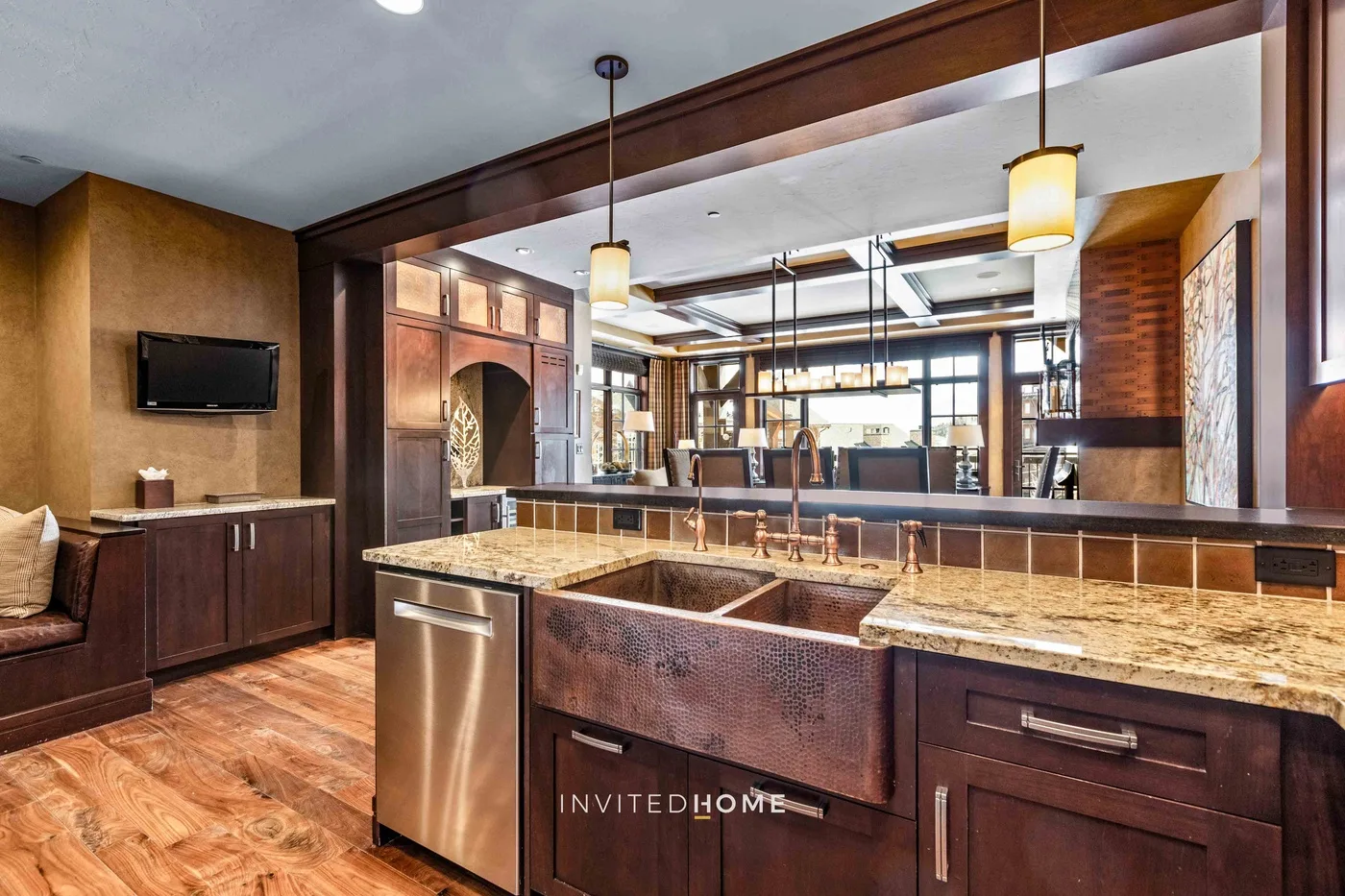 A kitchen with a large island, wood cabinetry, and pendant lights.