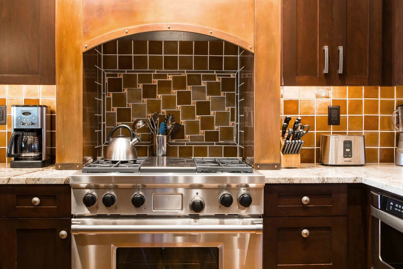 A kitchen with a stainless steel range beneath a tiled backsplash.