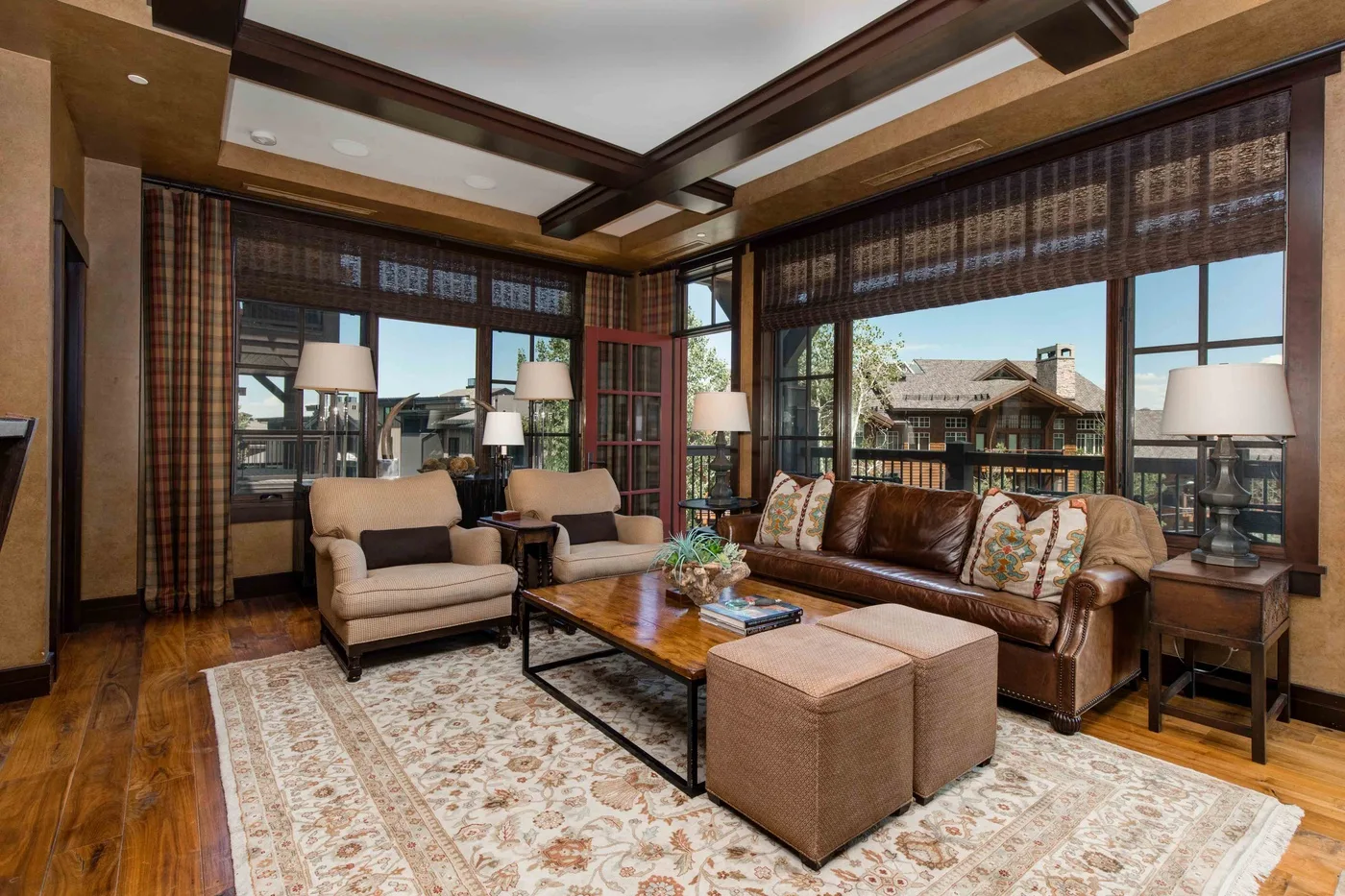 A living room with cushioned seating, a coffee table, and large windows.