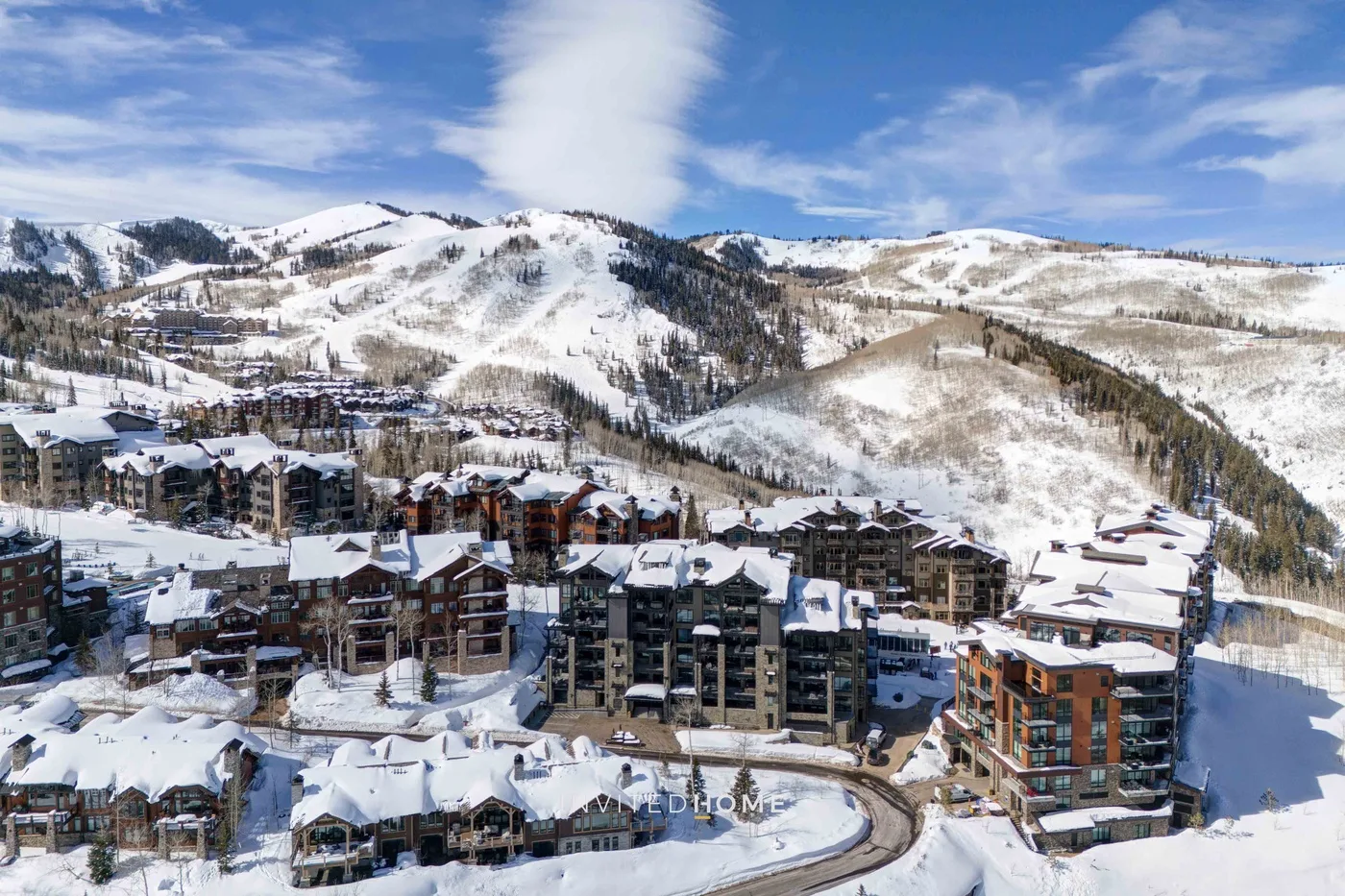 A snowy mountain resort with buildings clustered beneath ski slopes.