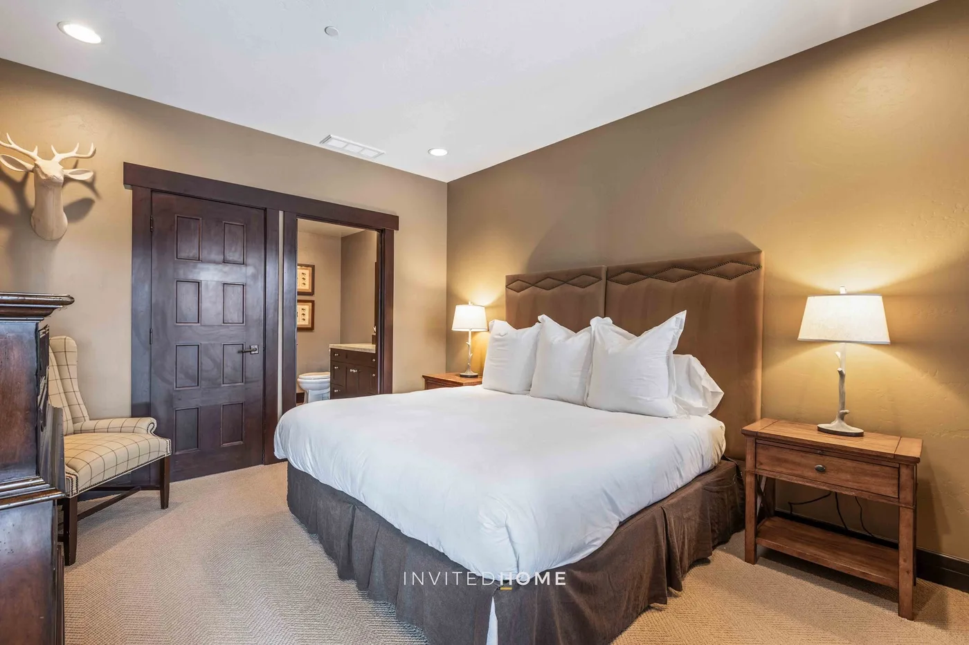 A bedroom with a large bed, bedside tables, and a patterned chair.