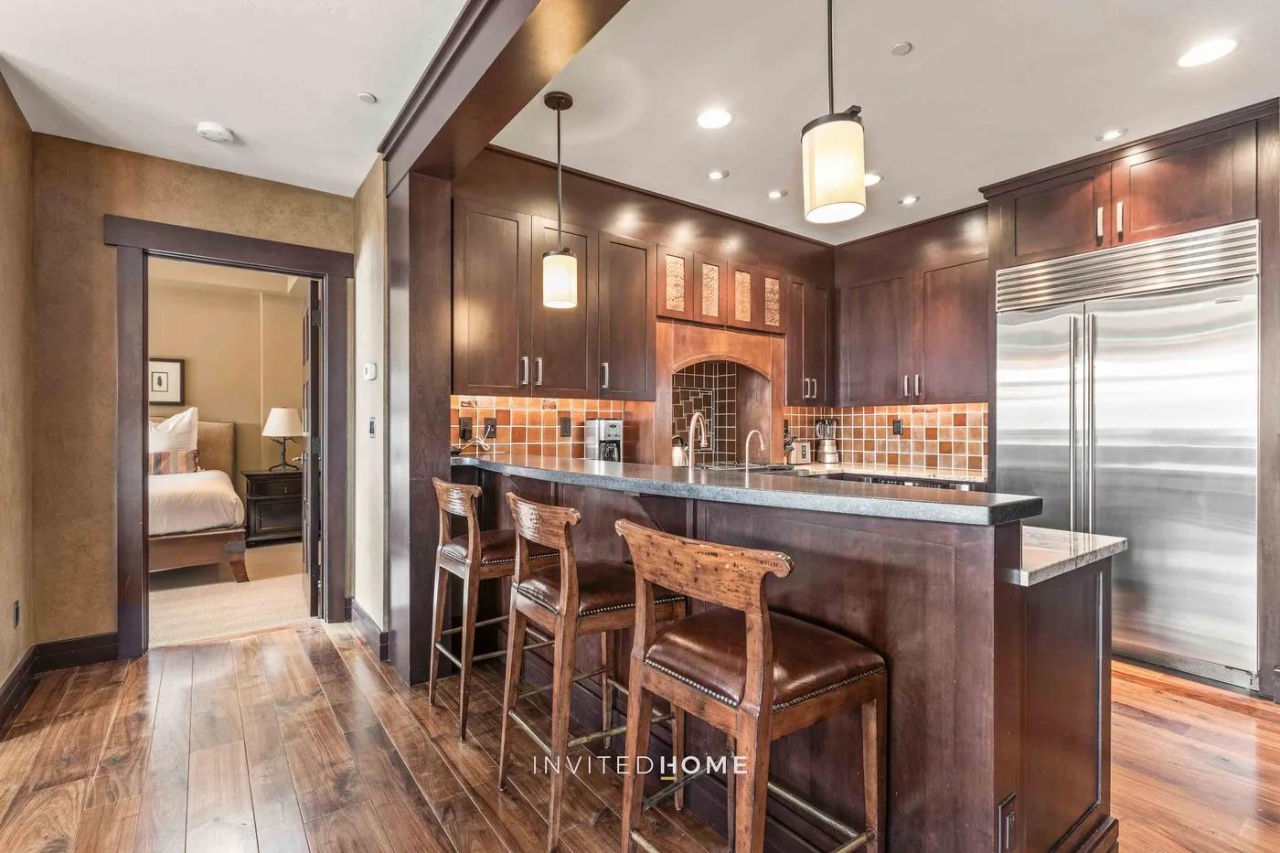 A kitchen with dark cabinets, a tiled backsplash, and a counter with seating.