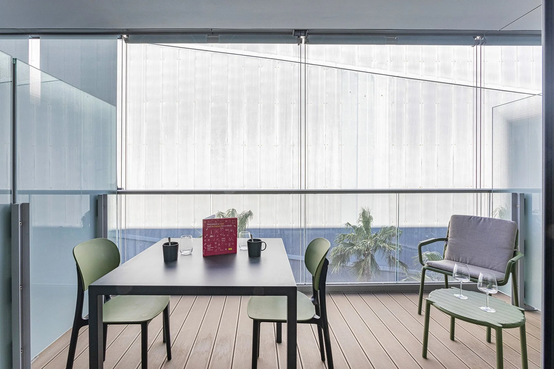 A dining table and seating sit beside a glass balcony railing.