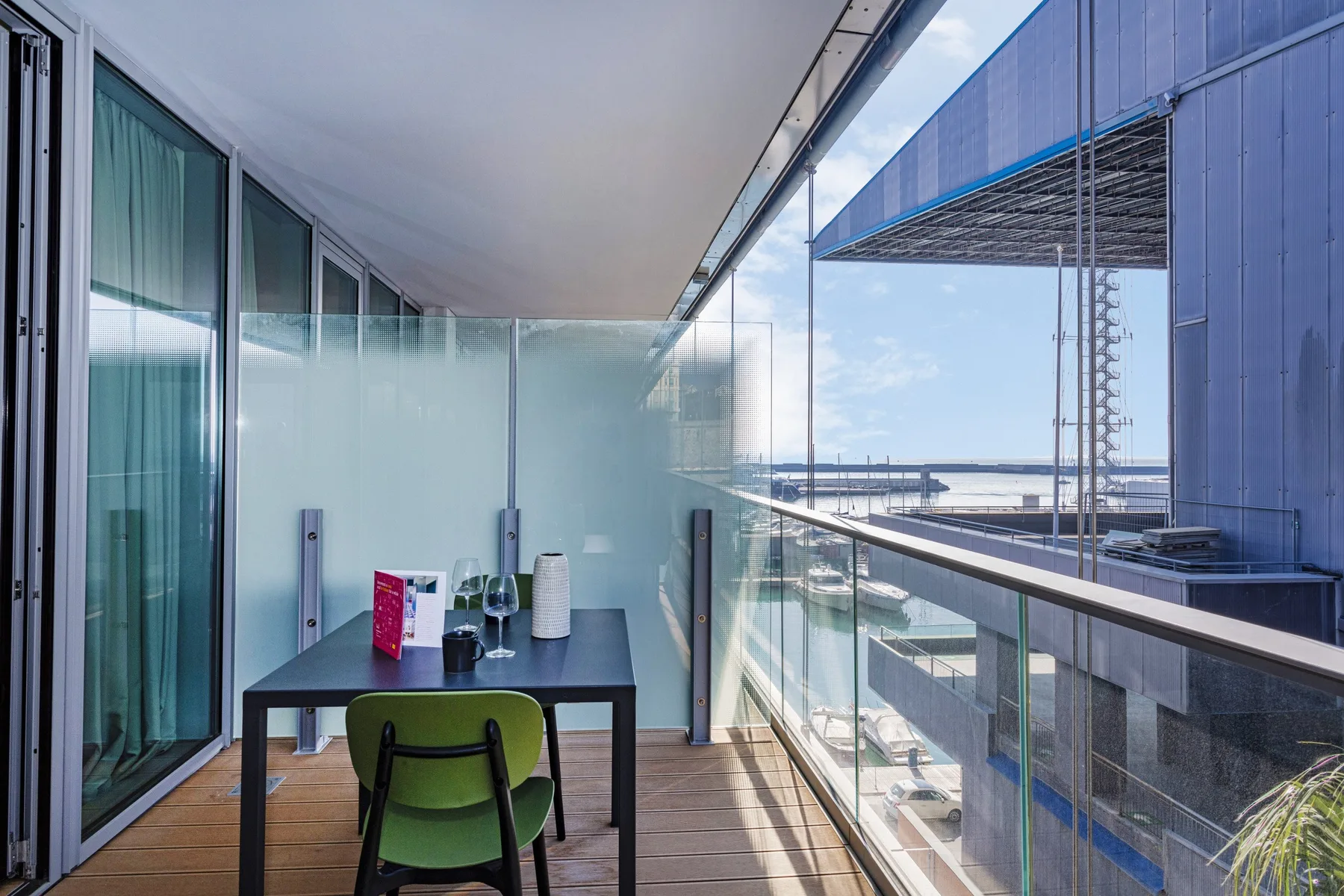 A balcony with a table and chairs overlooks the water.
