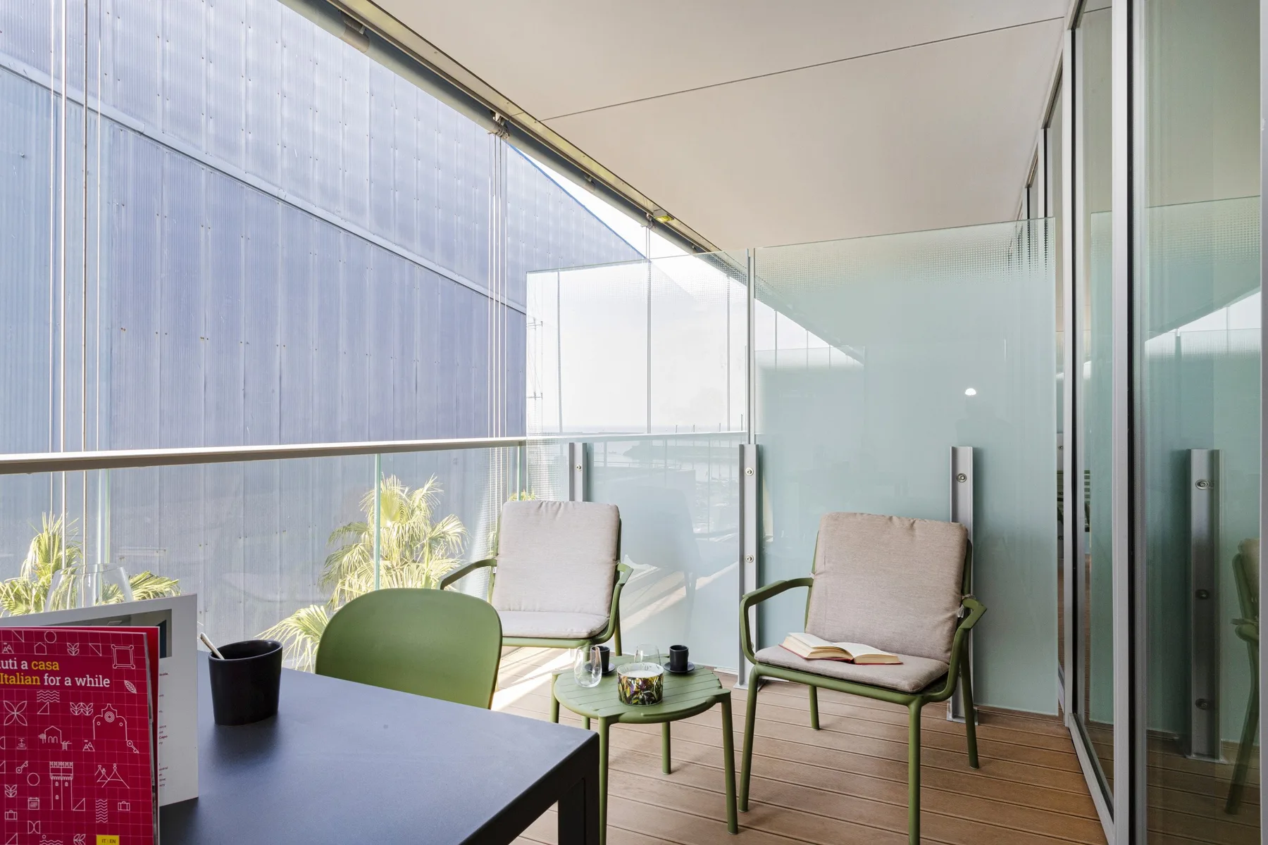 A balcony seating area with chairs and a small table beside glass walls.