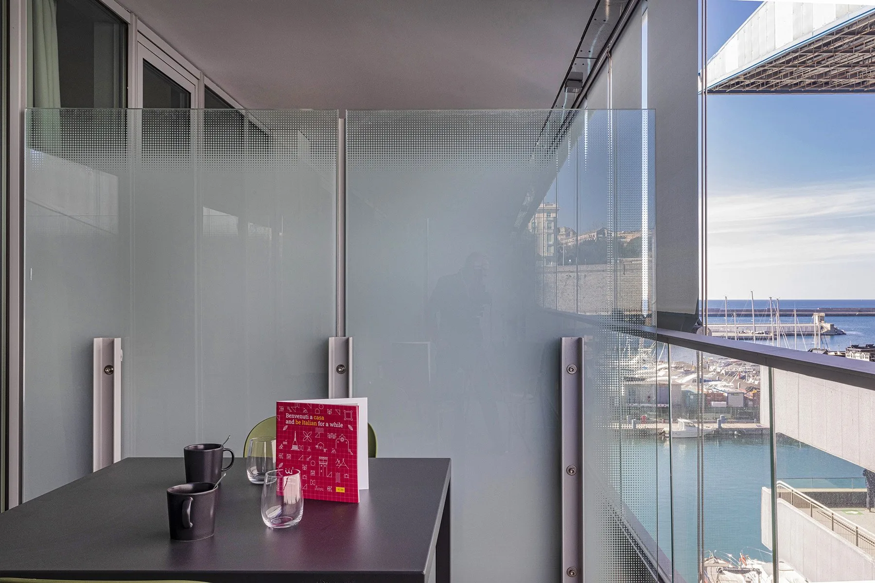 A balcony seating area with a table overlooks the water.