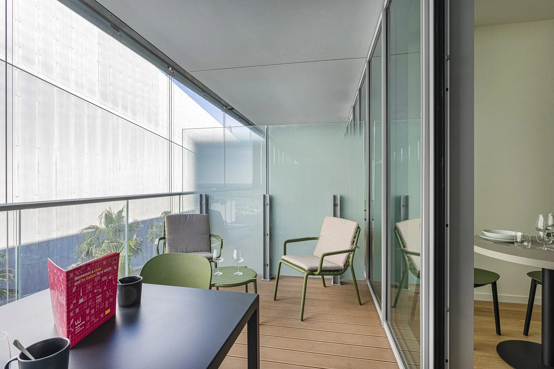 A glass-enclosed balcony with outdoor seating and a small table.