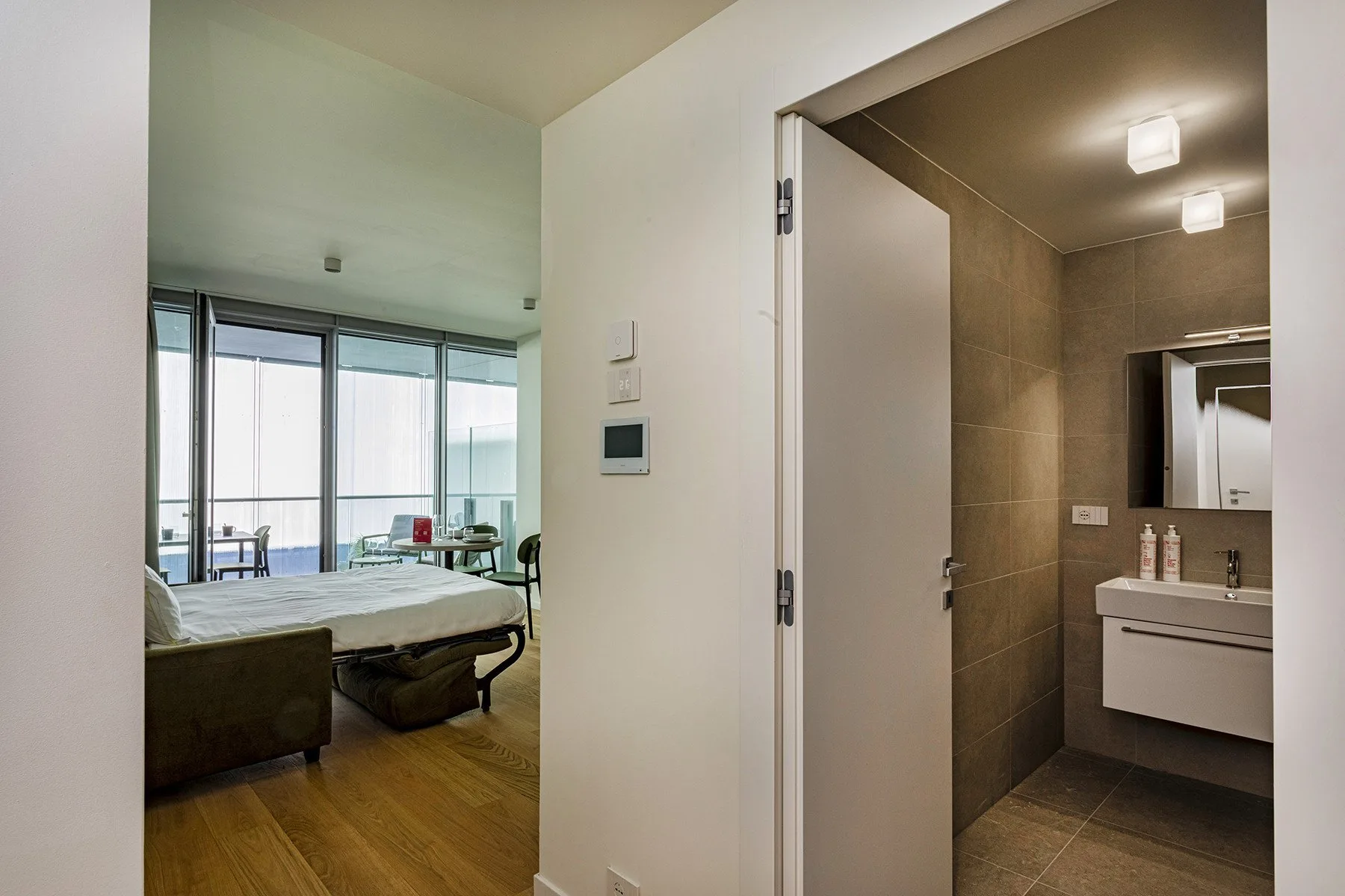 A bedroom with a bed beside an open doorway to a bathroom.