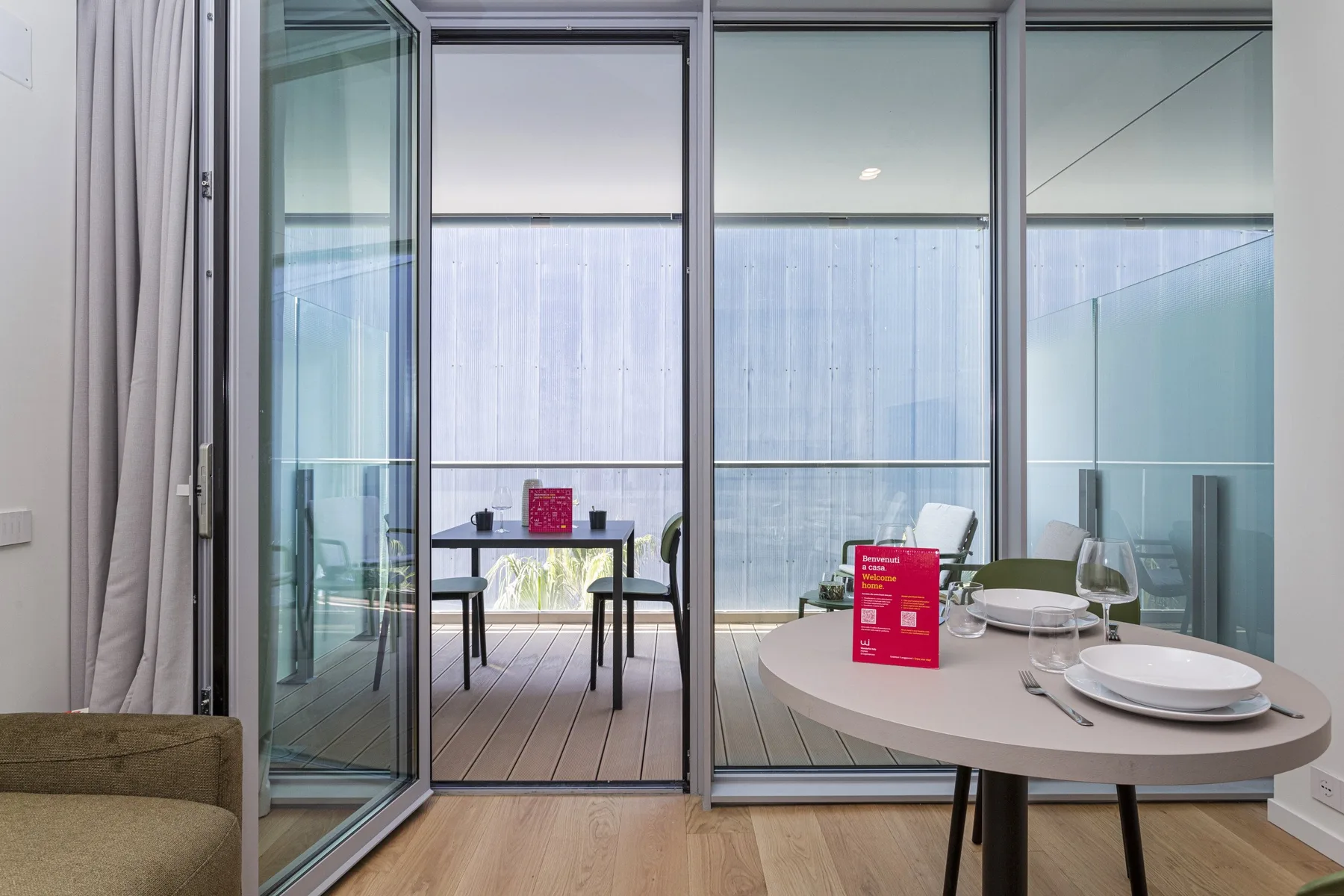 A dining area with a round table and chairs beside large windows.