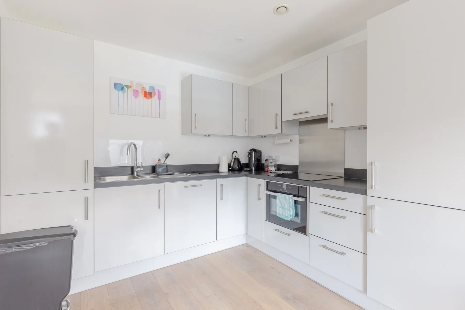A bright modern kitchen with white cabinets and dark countertops.