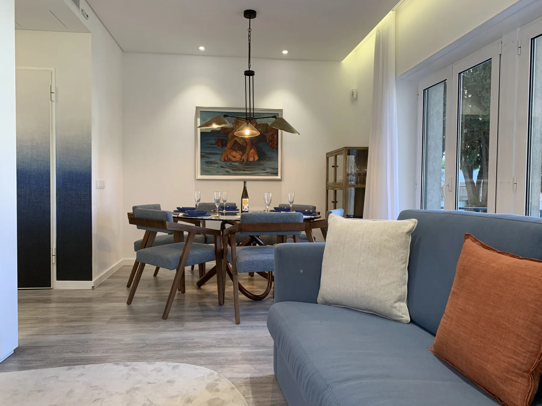 Zona de estar y comedor con asientos azules junto a una mesa puesta.