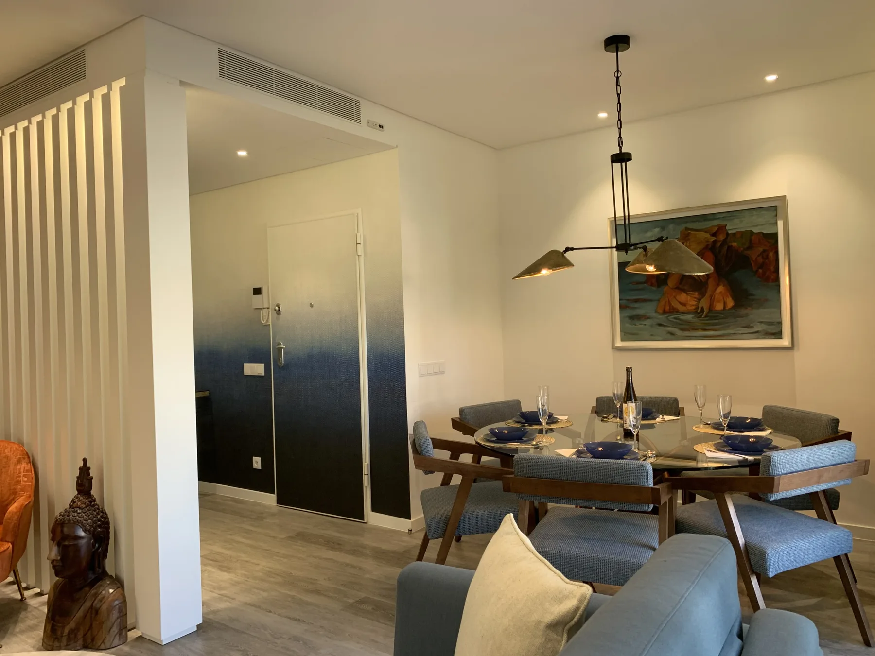 Un comedor con la mesa puesta junto a una puerta de entrada oscura.