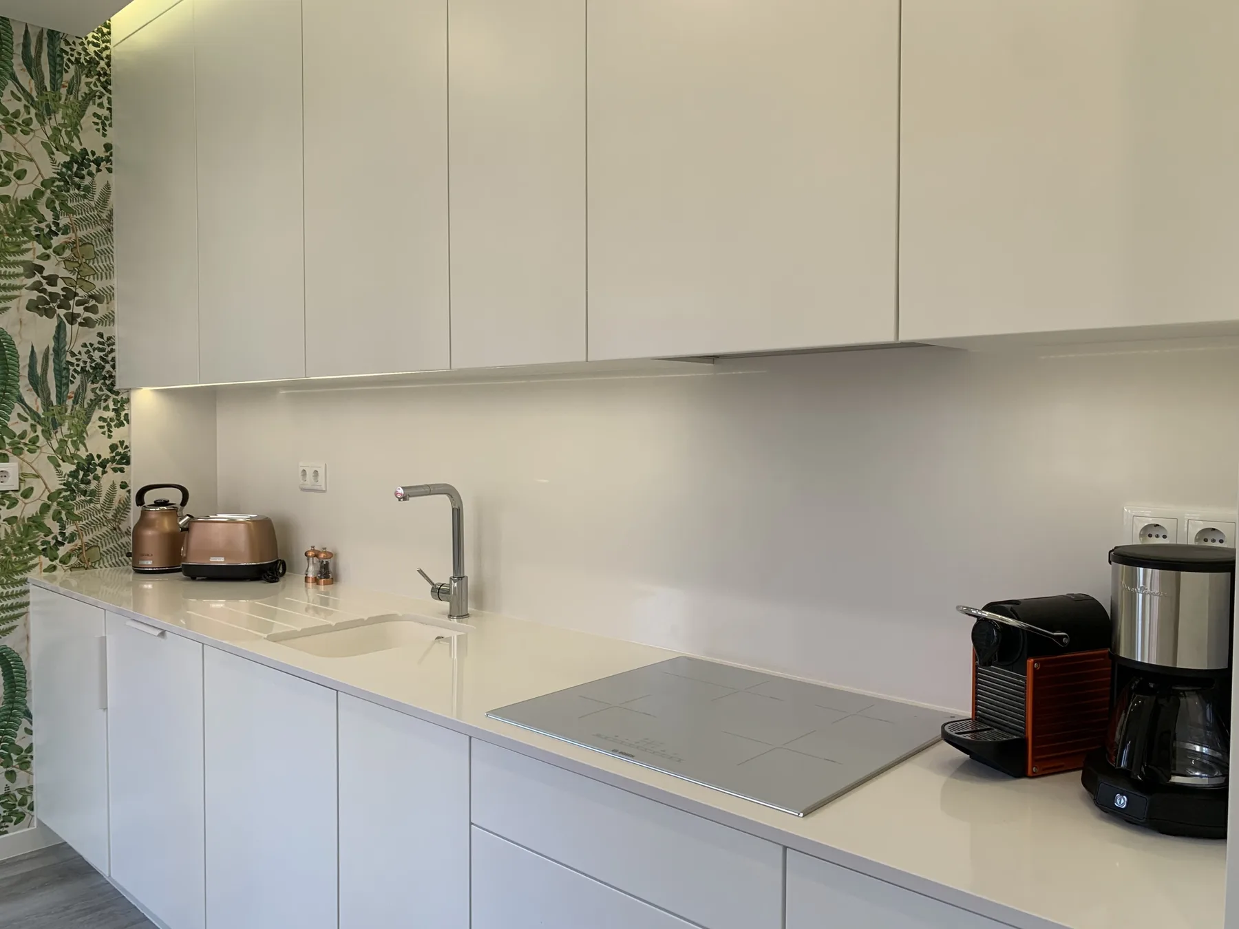 Una cocina moderna con armarios blancos, una encimera y una placa de cocción.