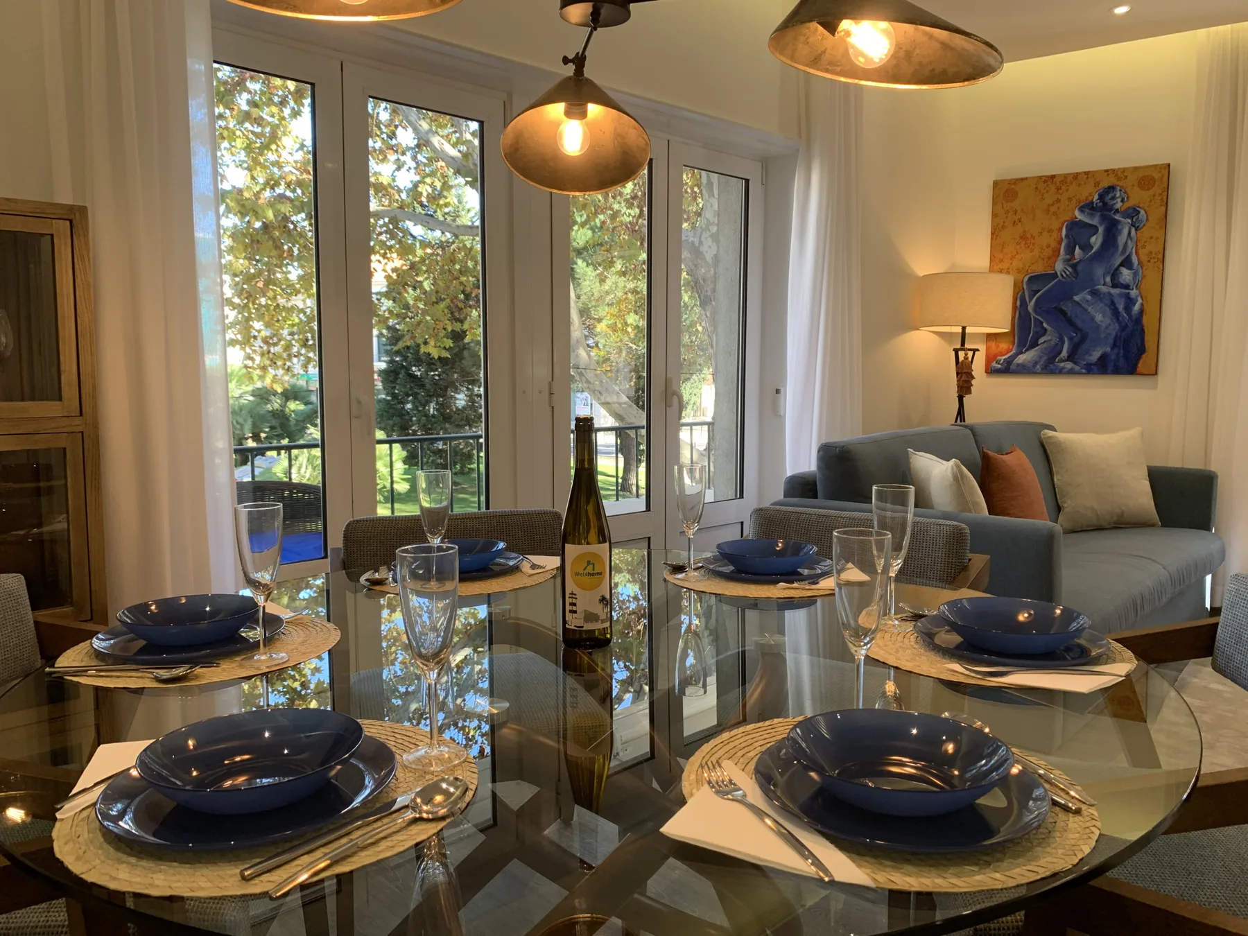 Comedor y sala de estar con la mesa puesta junto a grandes ventanales.