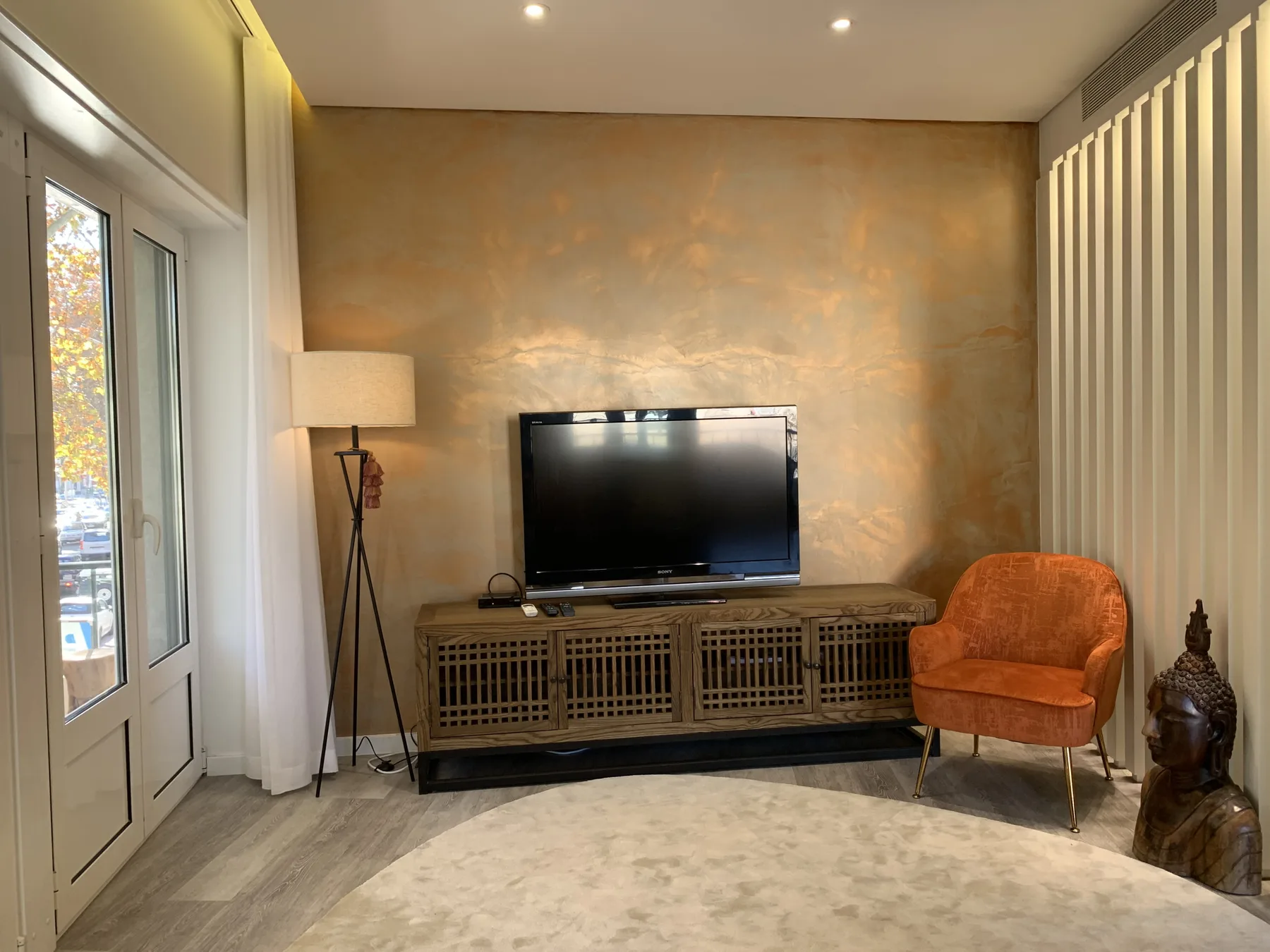 Sala de estar con un televisor sobre una consola de madera y un asiento naranja.