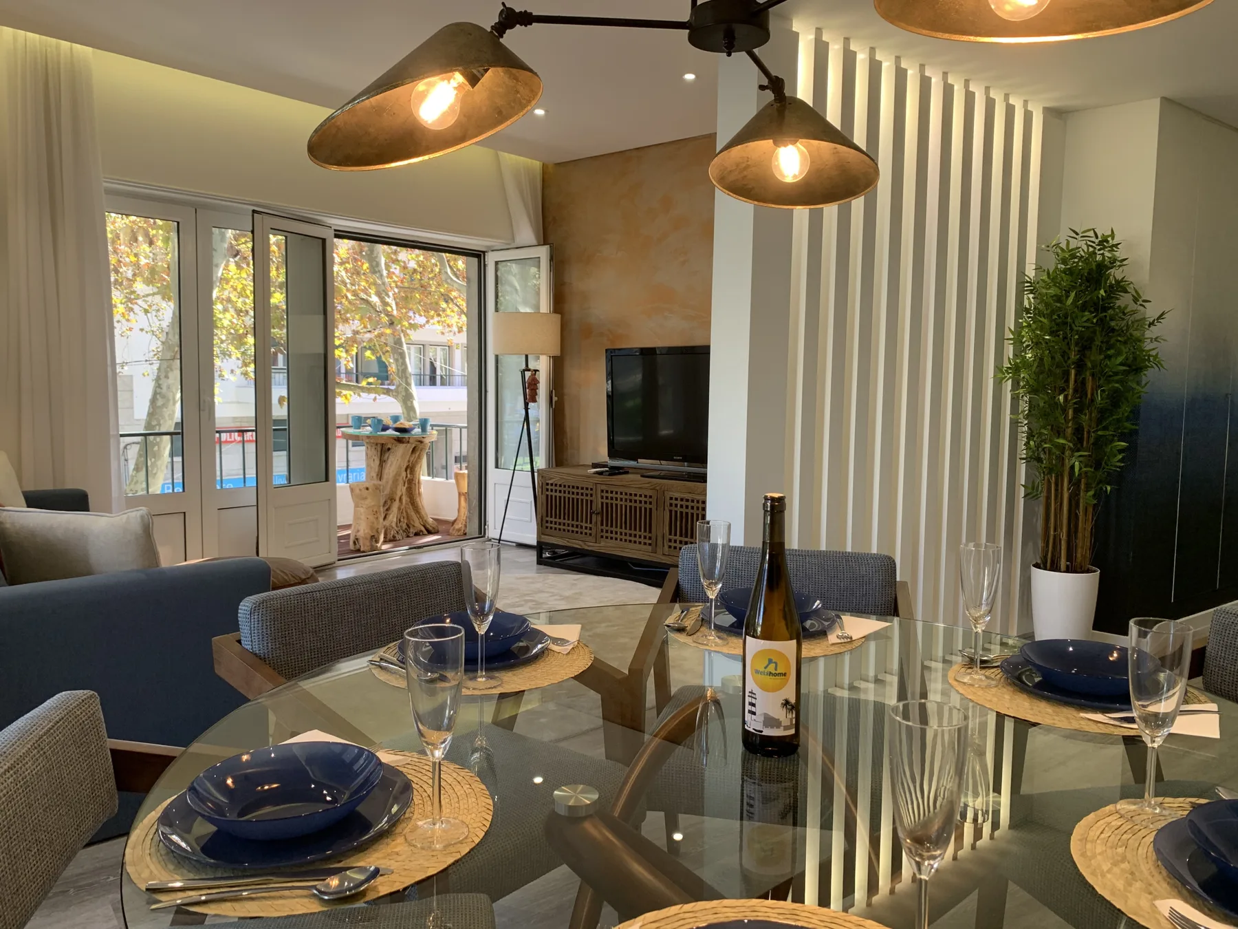 Una sala de estar y comedor moderna con puertas de vidrio que dan a un balcón.