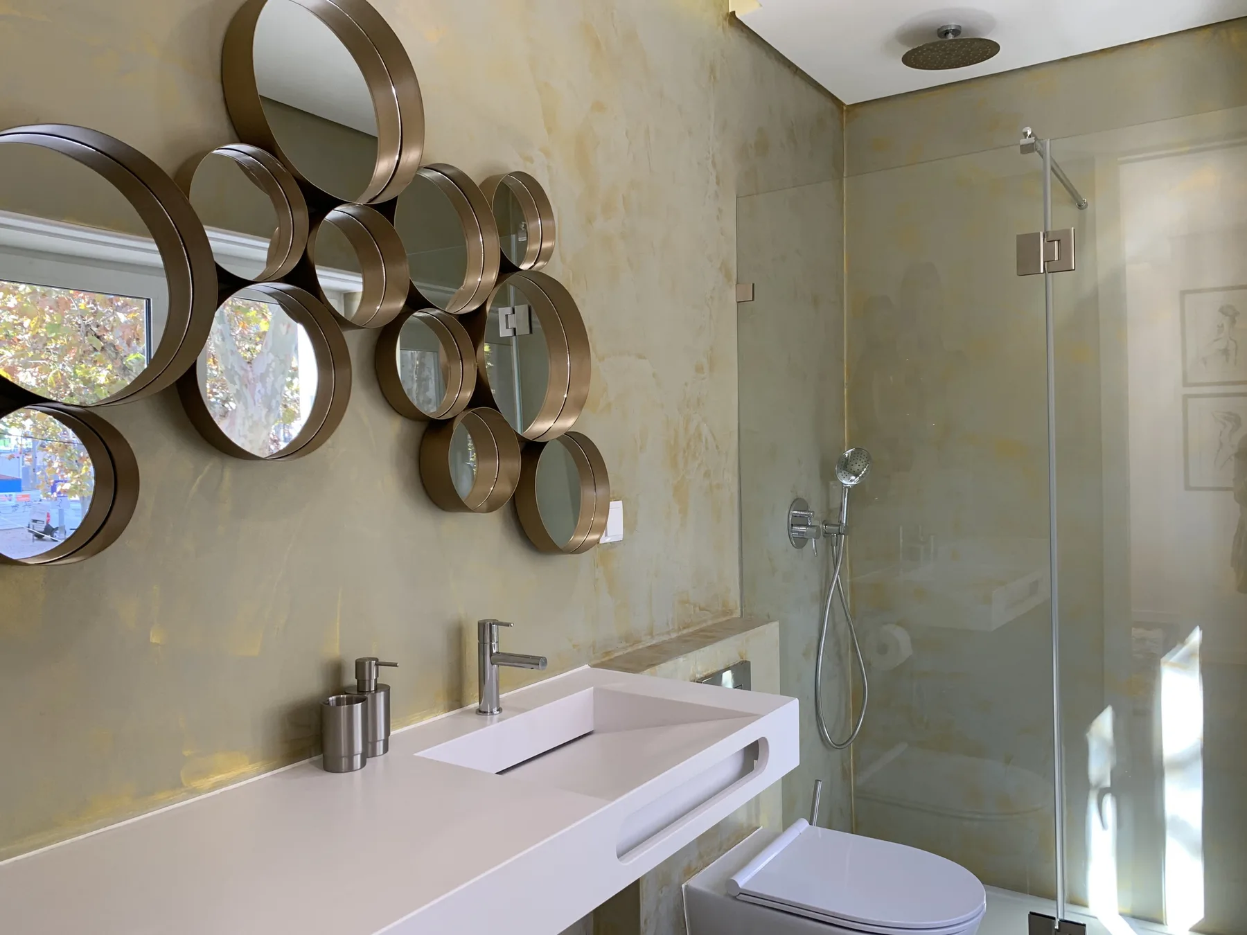 Un baño con una encimera de lavabo alargada y una ducha de vidrio.