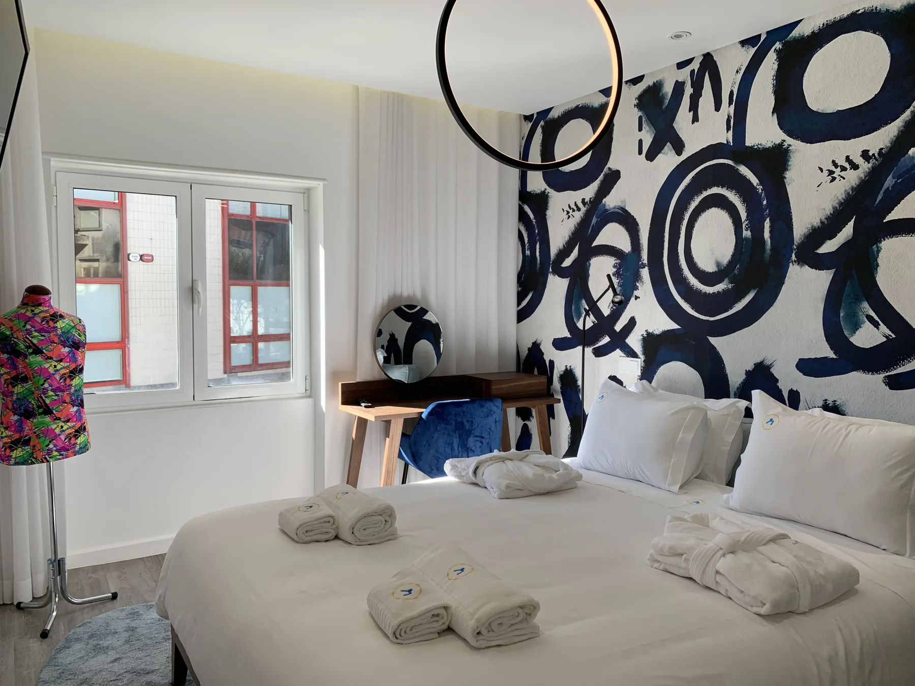 Dormitorio con una cama grande, una ventana y arte llamativo en la pared.