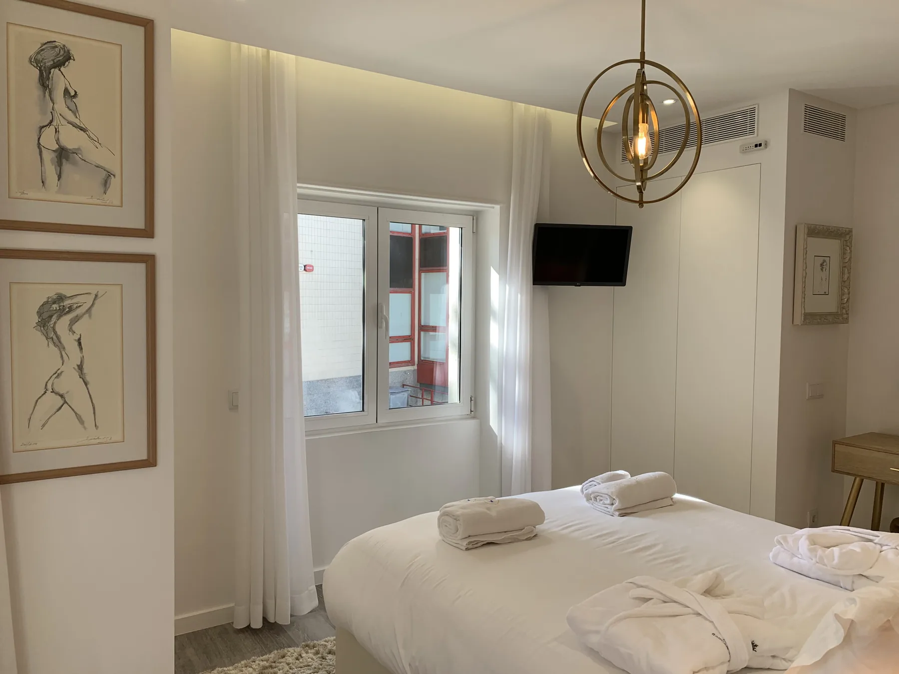 Un dormitorio con una cama bien arreglada y un televisor montado en la pared.