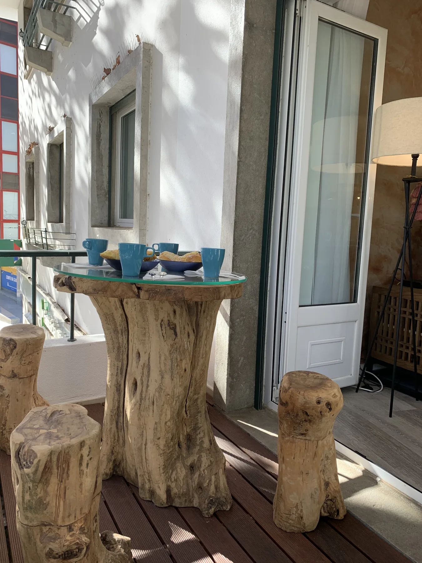 Un pequeño patio exterior tiene una mesa rústica de madera con platos azules.