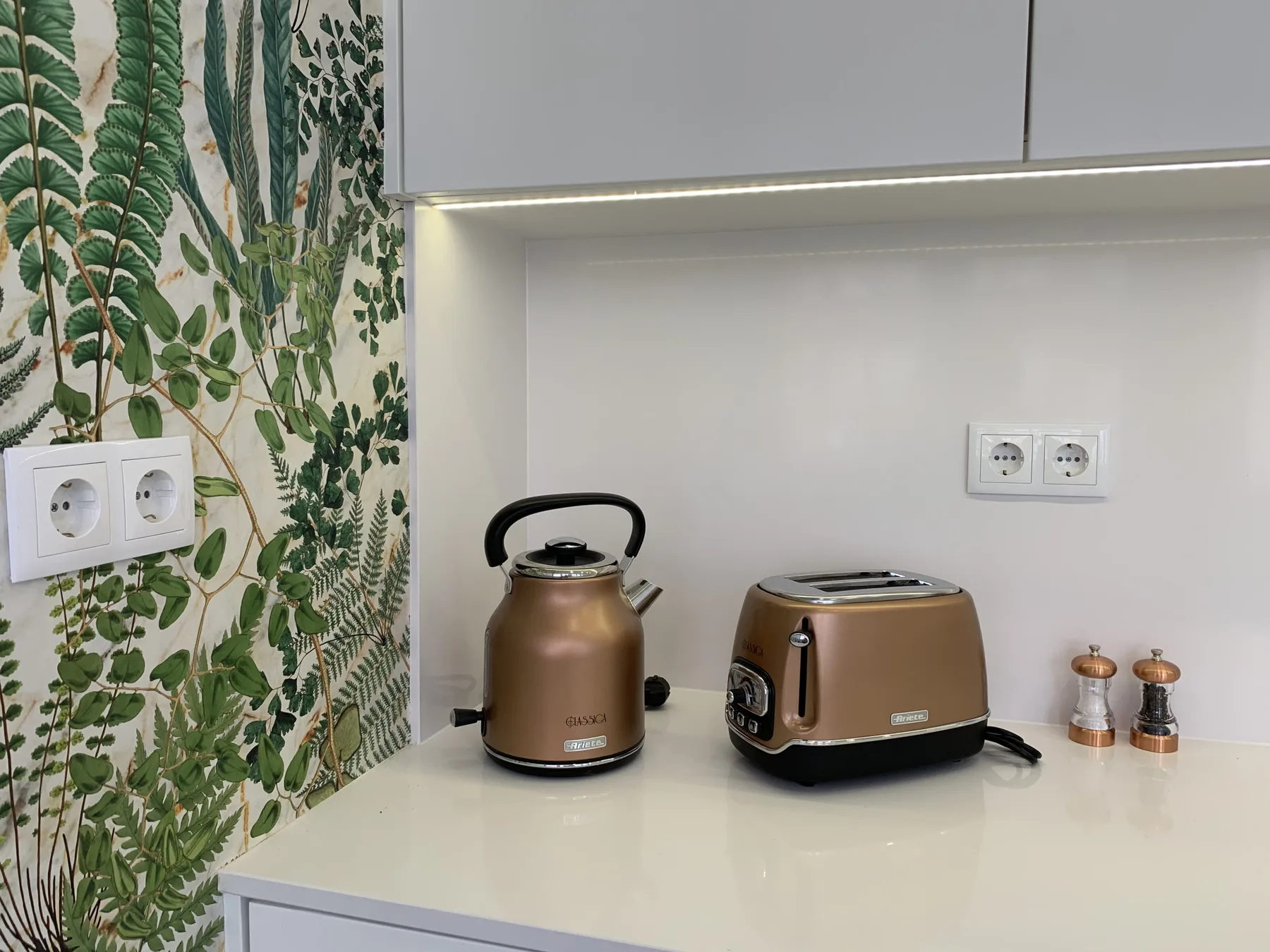 Una encimera de cocina con un hervidor y una tostadora bajo los armarios.