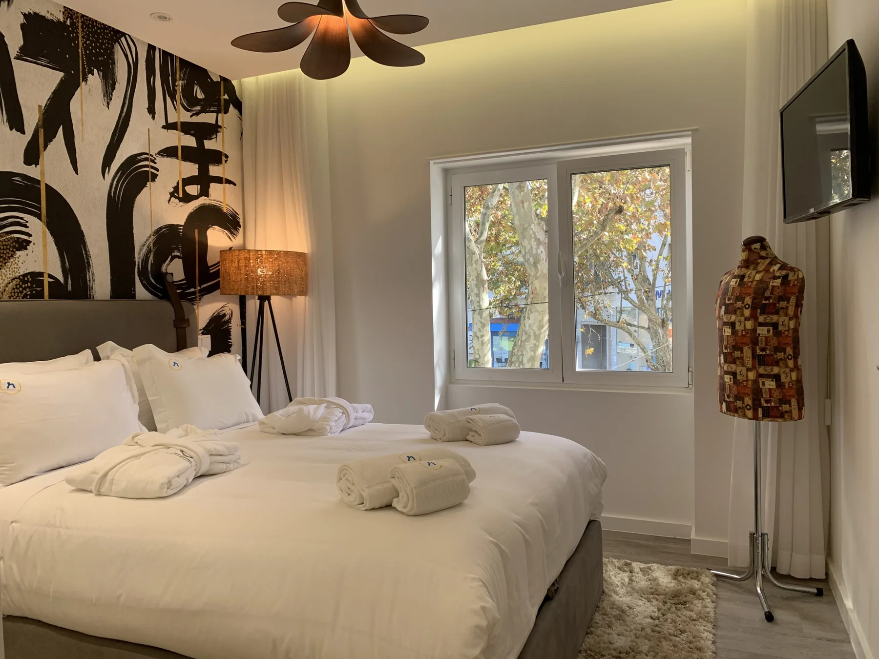Un dormitorio con una cama tendida y una ventana con vistas a los árboles.