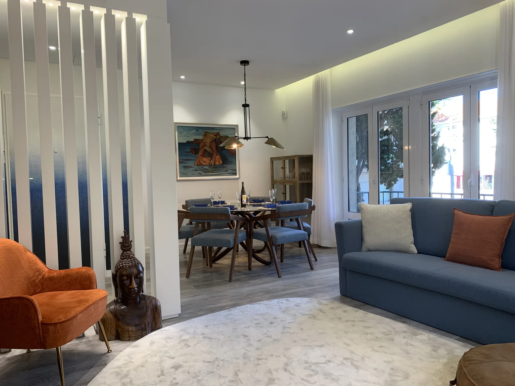 Una sala de estar y comedor con un sofá azul y una mesa de comedor de madera.