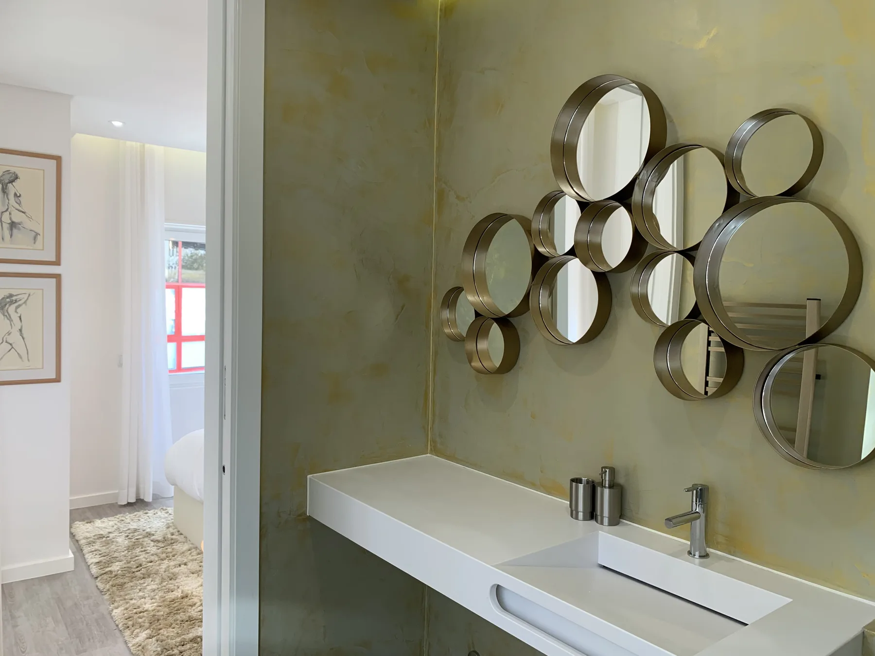 Un baño con un lavabo blanco alargado y espejos circulares en la pared.