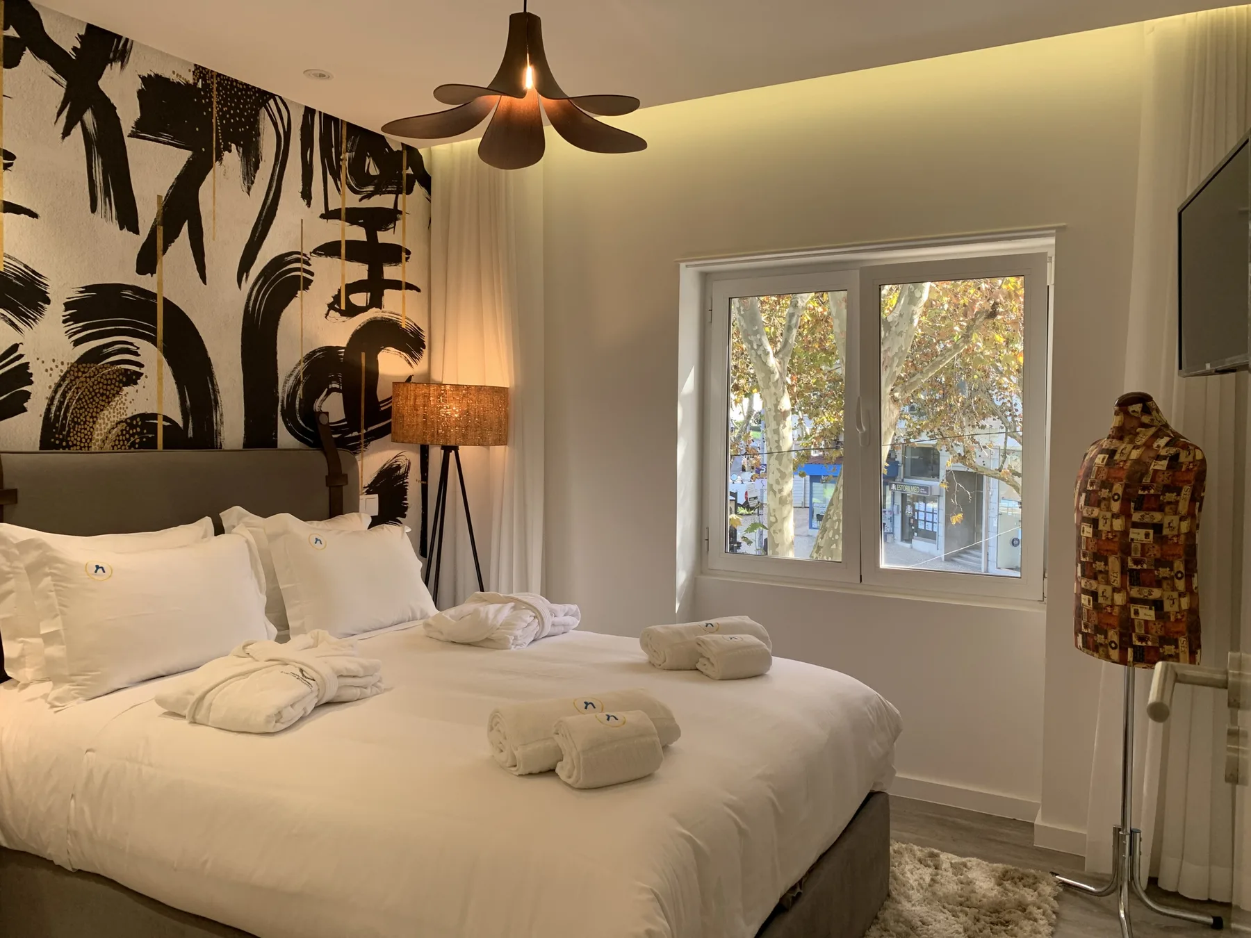 Un dormitorio con una cama grande, una pared estampada y una ventana.