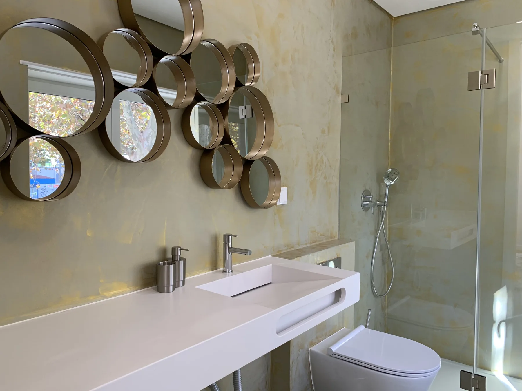 Un baño moderno con un lavabo blanco alargado y una ducha de cristal.