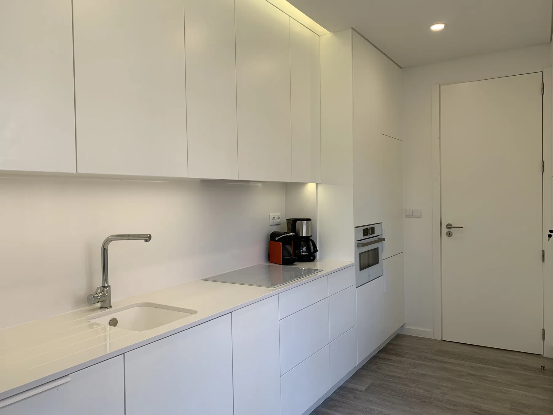 Una cocina moderna con armarios blancos, una encimera y electrodomésticos integrados.