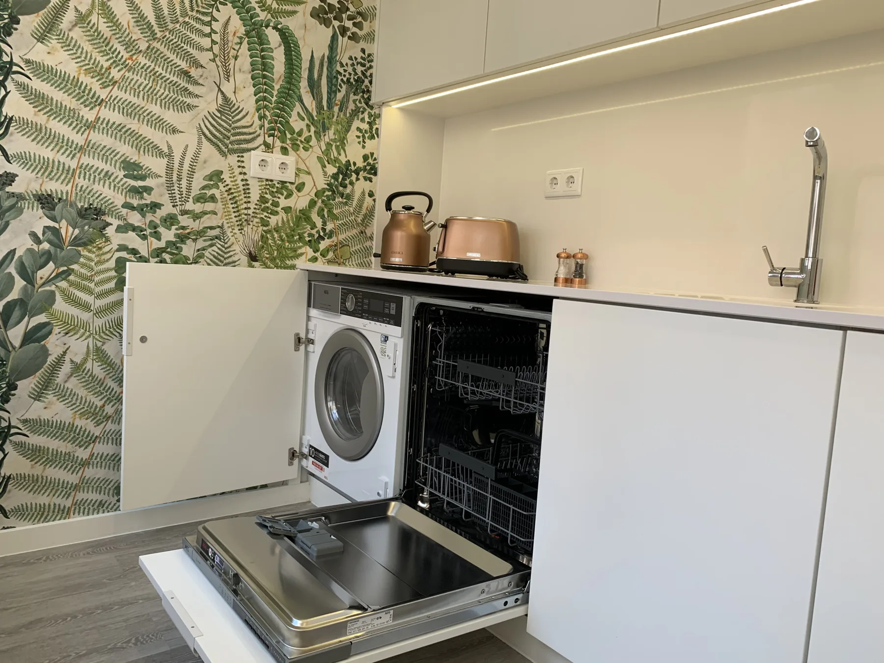 Una pequeña zona de cocina con una lavadora y un lavavajillas abierto.