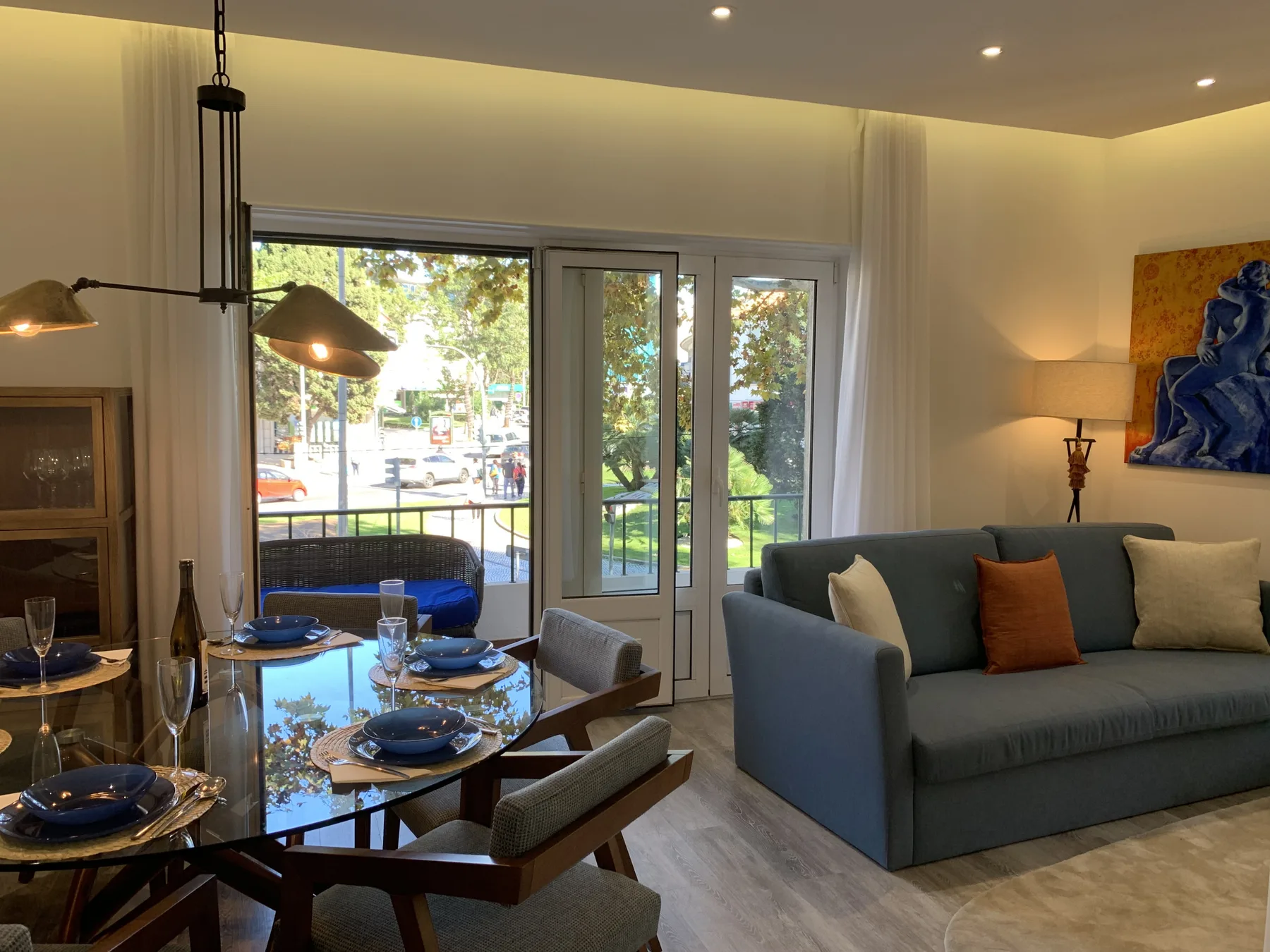Una sala de estar y comedor con sofá, mesa y puertas de vidrio que dan a un balcón.