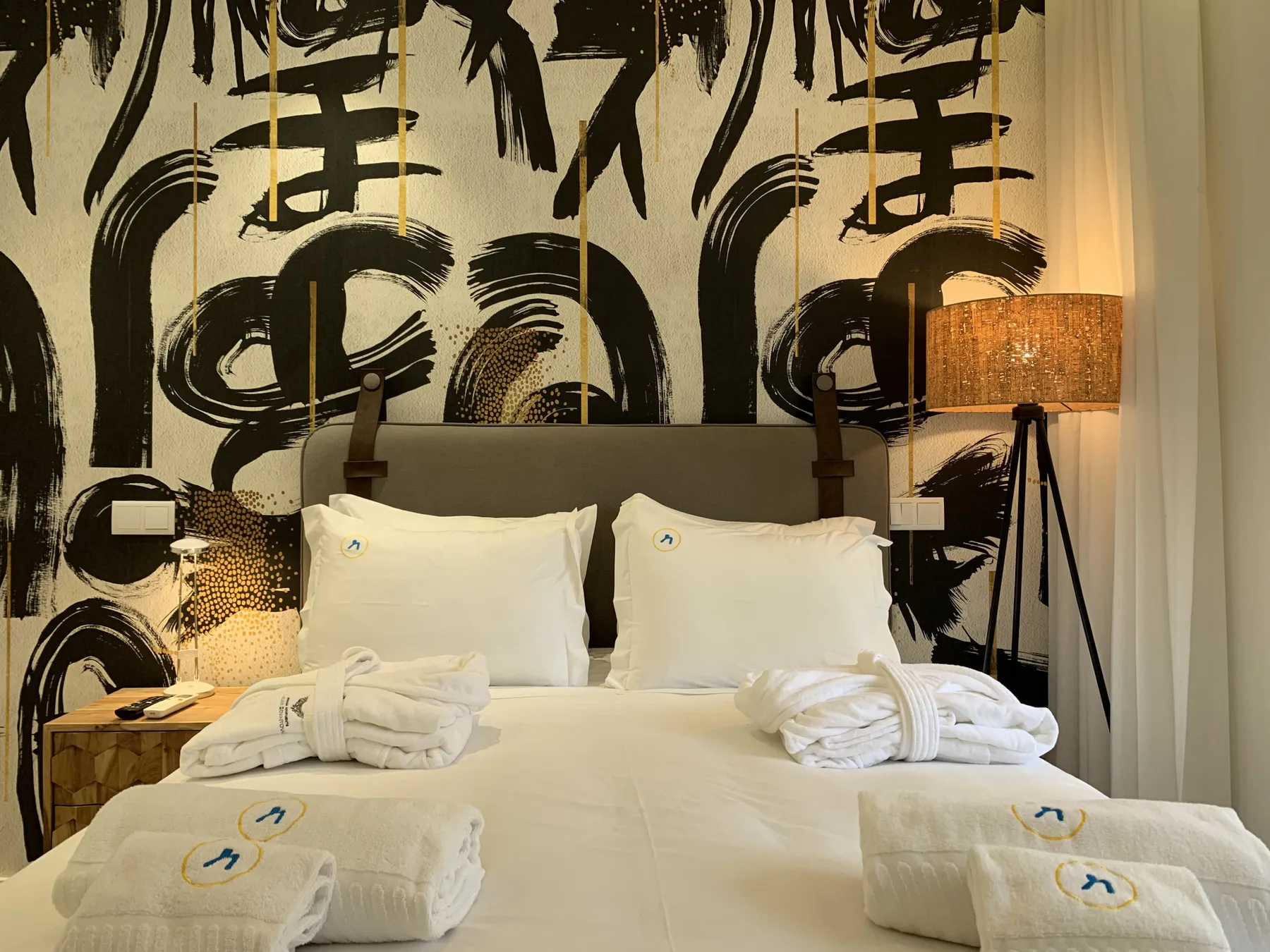 Un dormitorio con una cama tendida y un llamativo mural en blanco y negro.