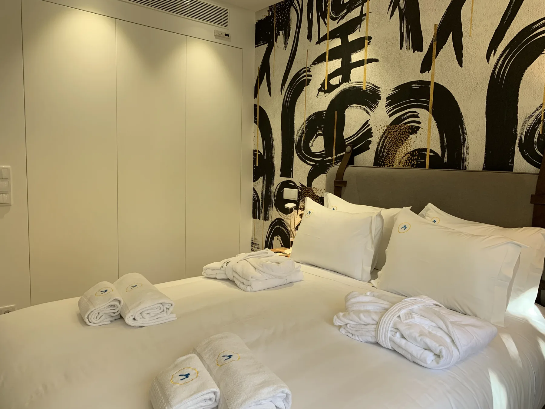 Dormitorio con una cama arreglada y toallas dobladas.