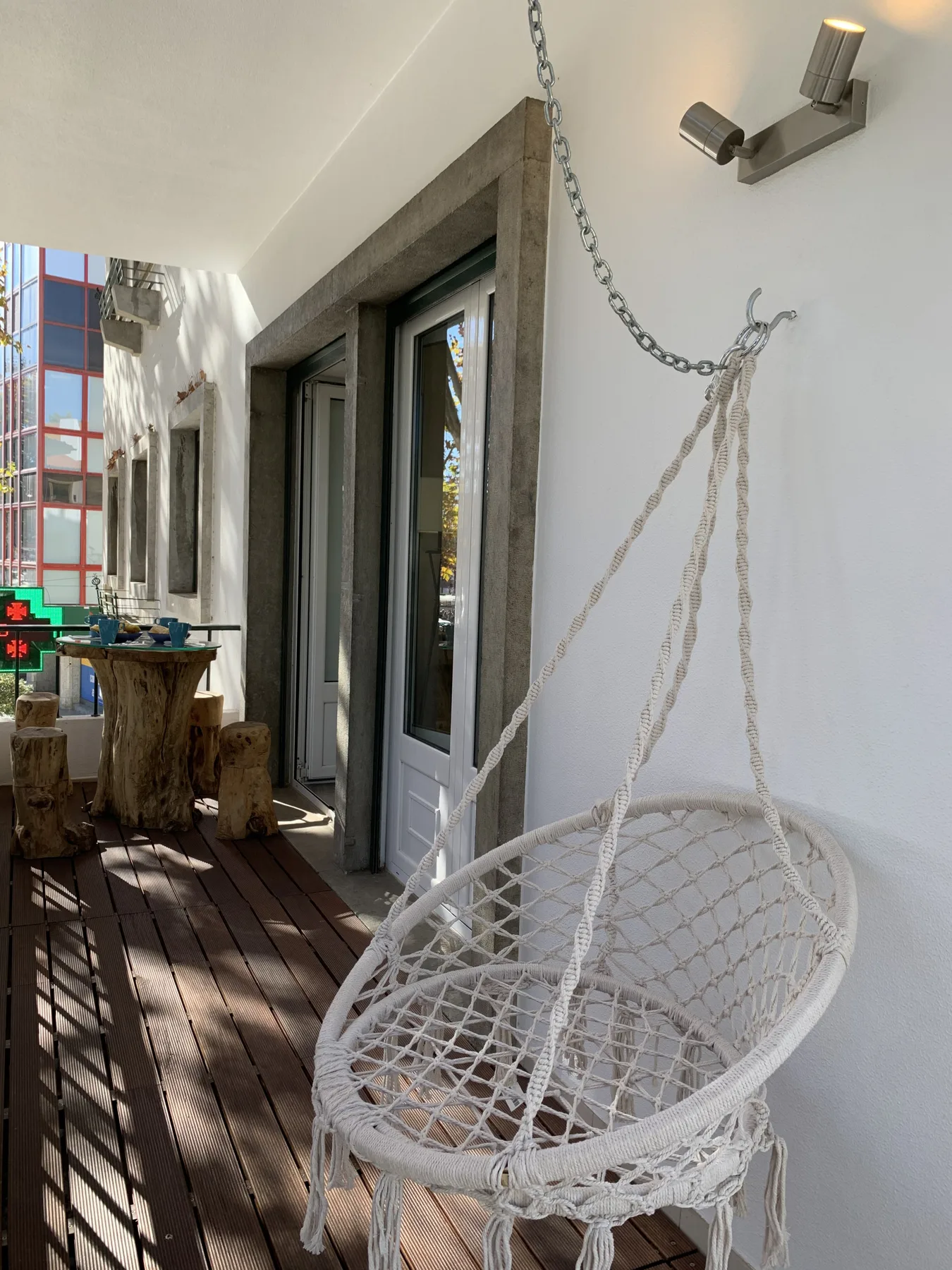 Una zona de estar exterior cubierta con una silla colgante tejida junto a puertas de vidrio.