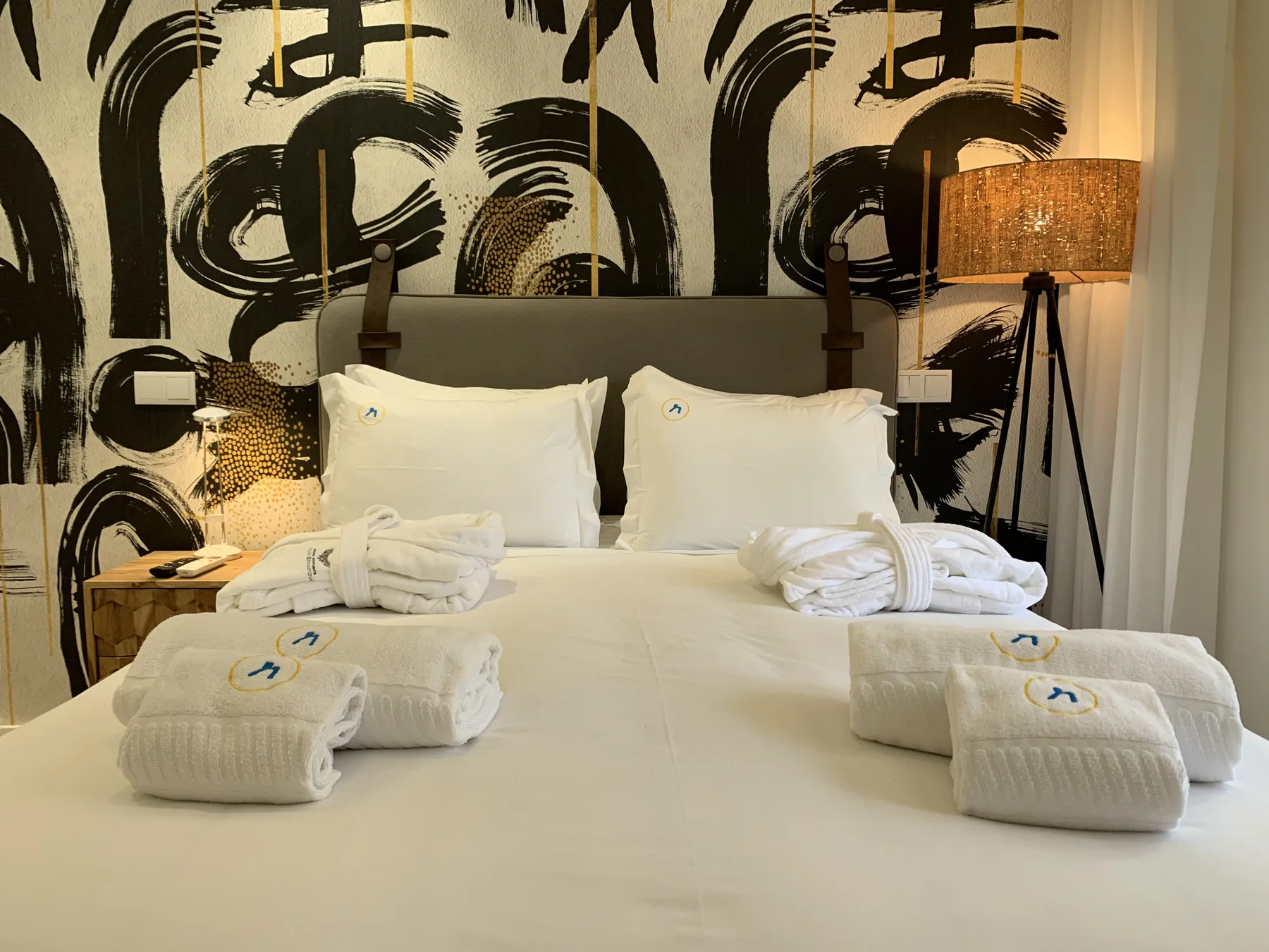 Un dormitorio con una cama grande, ropa de cama blanca y un llamativo mural en blanco y negro.