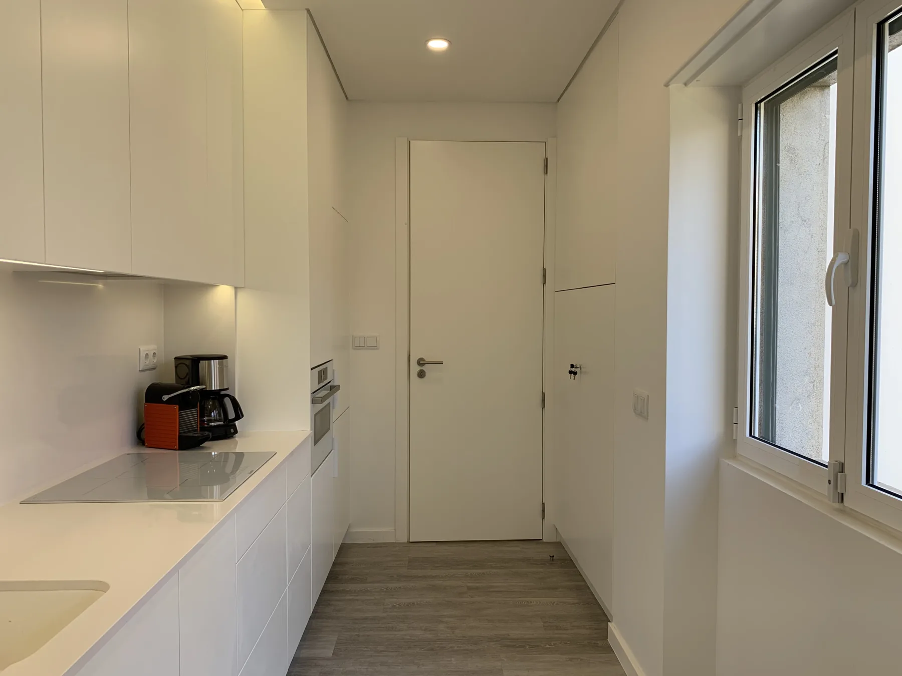 Una cocina compacta con gabinetes blancos, una encimera y una ventana.