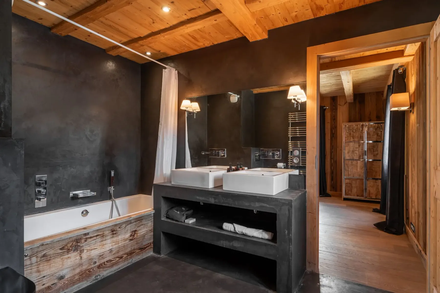 Baño con bañera, dos lavabos y techo de madera.