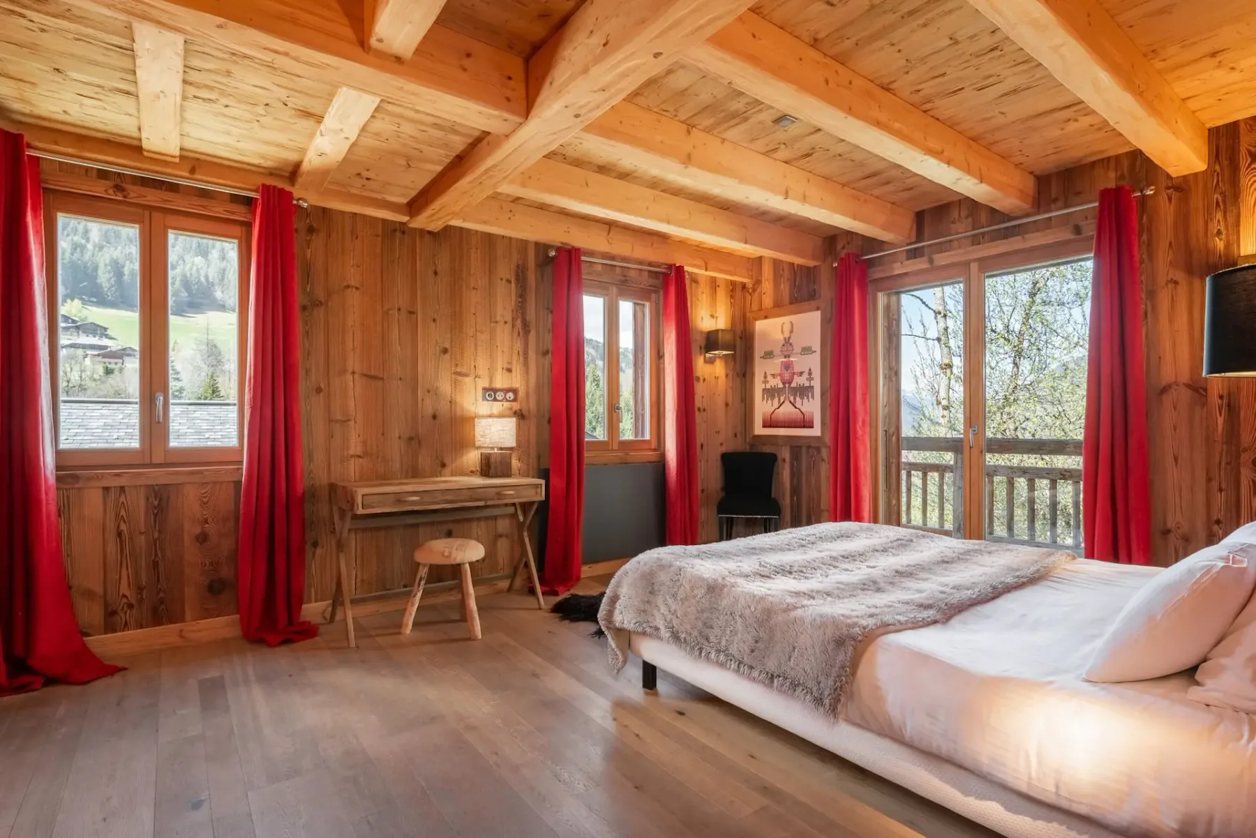 Un dormitorio revestido de madera con una cama y grandes ventanas enmarcadas por cortinas rojas.